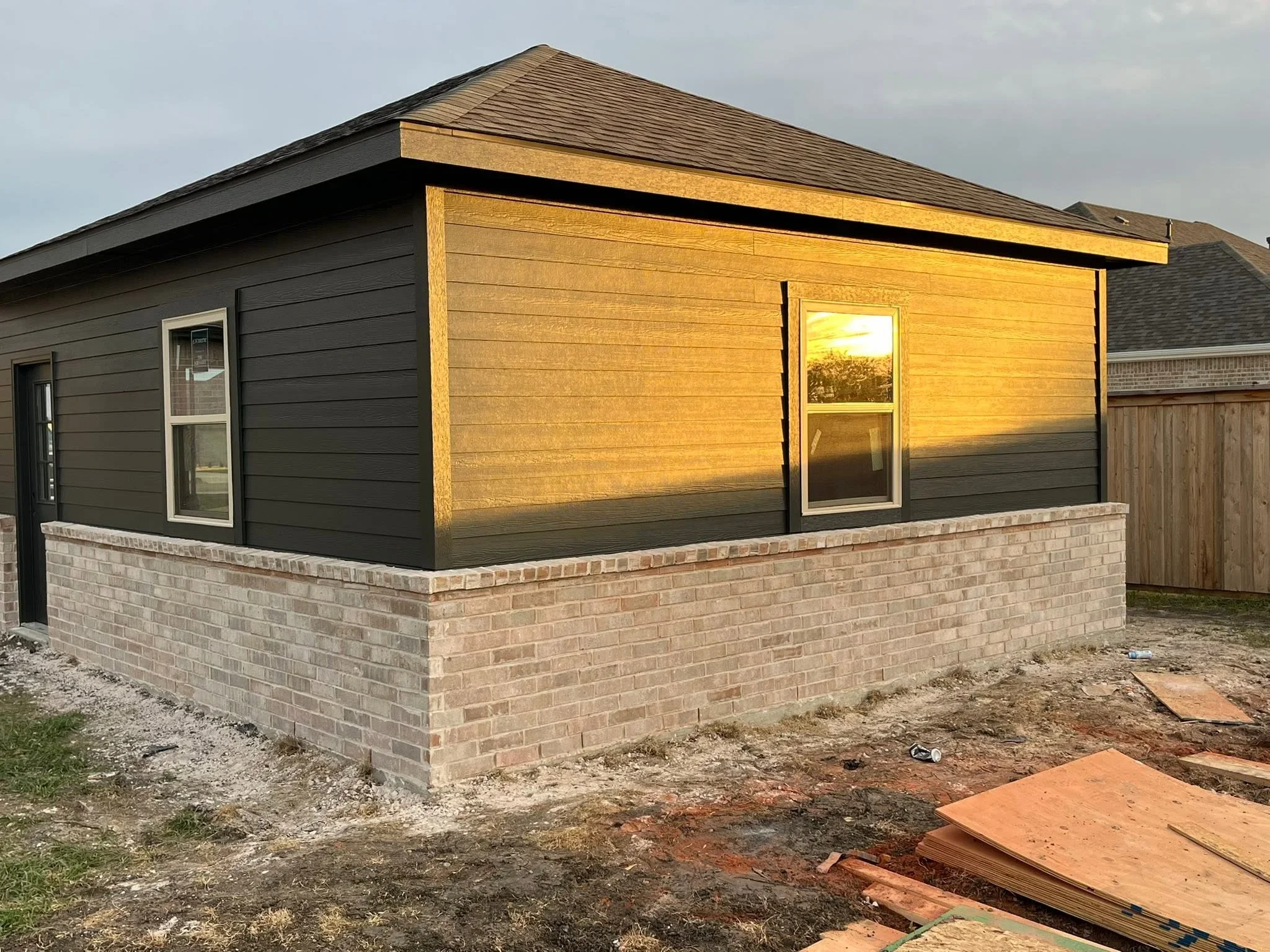 New home addition with brick base, horizontal wood siding, and shingled roof