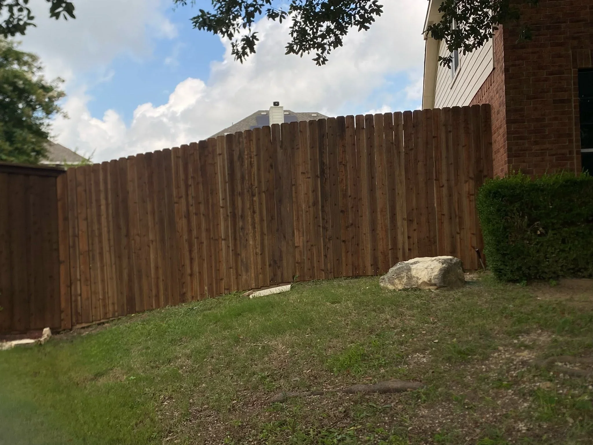 Vertical wood privacy fence with natural stain finish installed in residential backyard