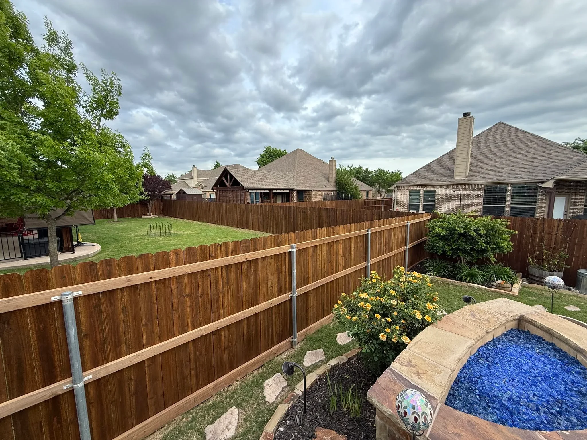 Cedar wood privacy fence with metal rails and posts surrounding residential backyard with pool