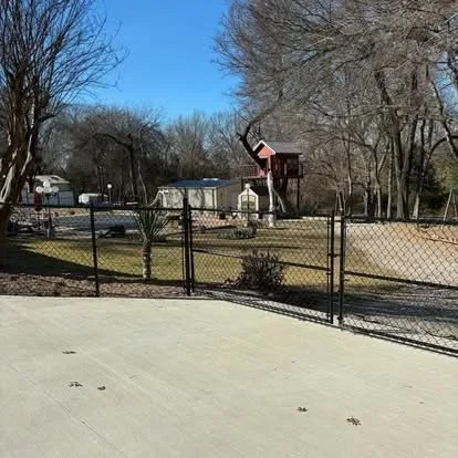 Black vinyl-coated chain-link fence with gate installed around residential property