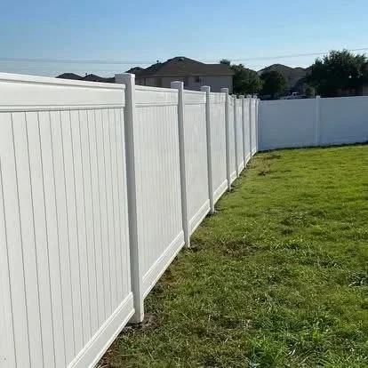 White vinyl privacy fence with vertical boards installed along residential property with green lawn