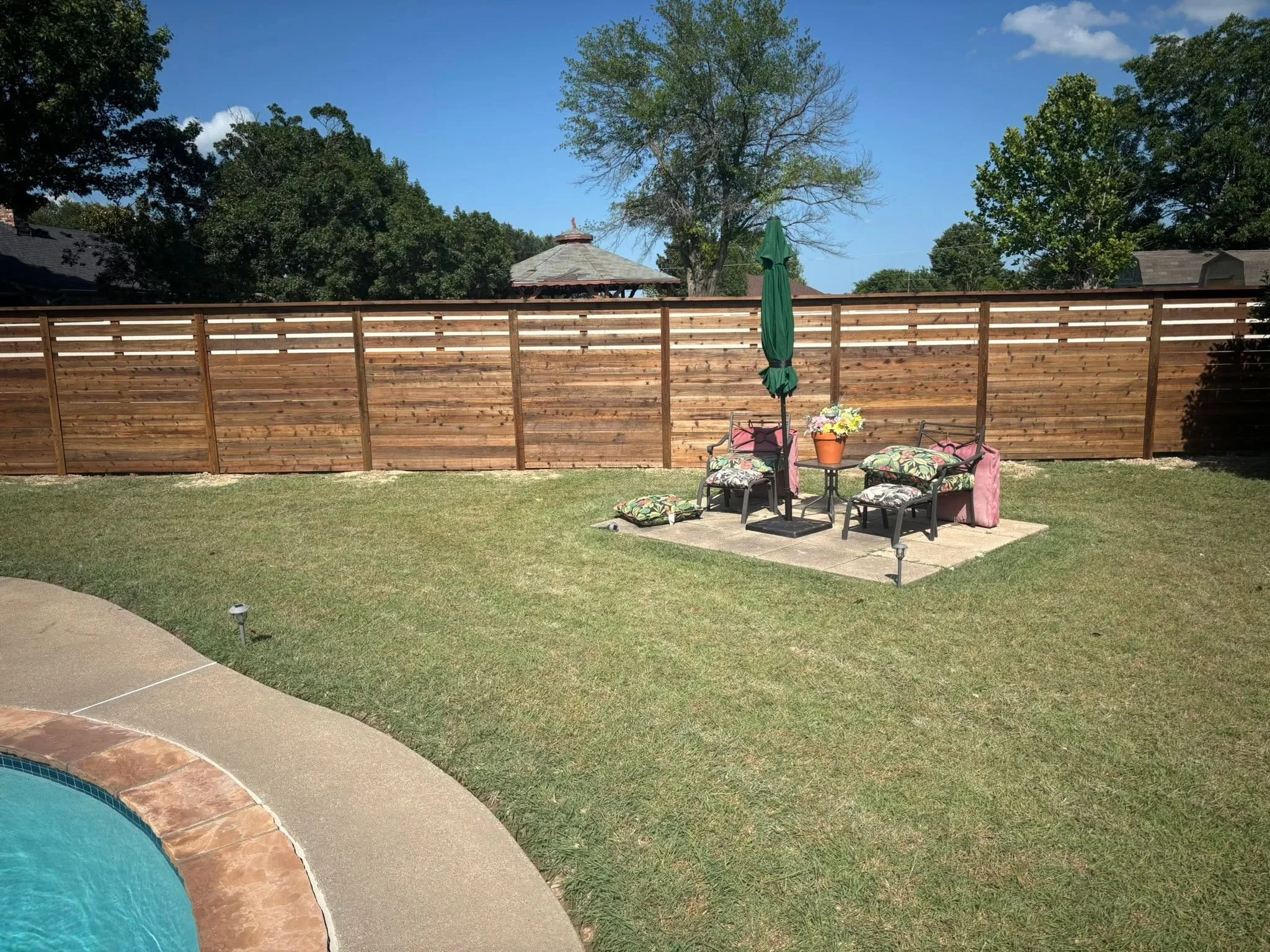 Horizontal wood privacy fence with slatted design and vertical posts in residential backyard