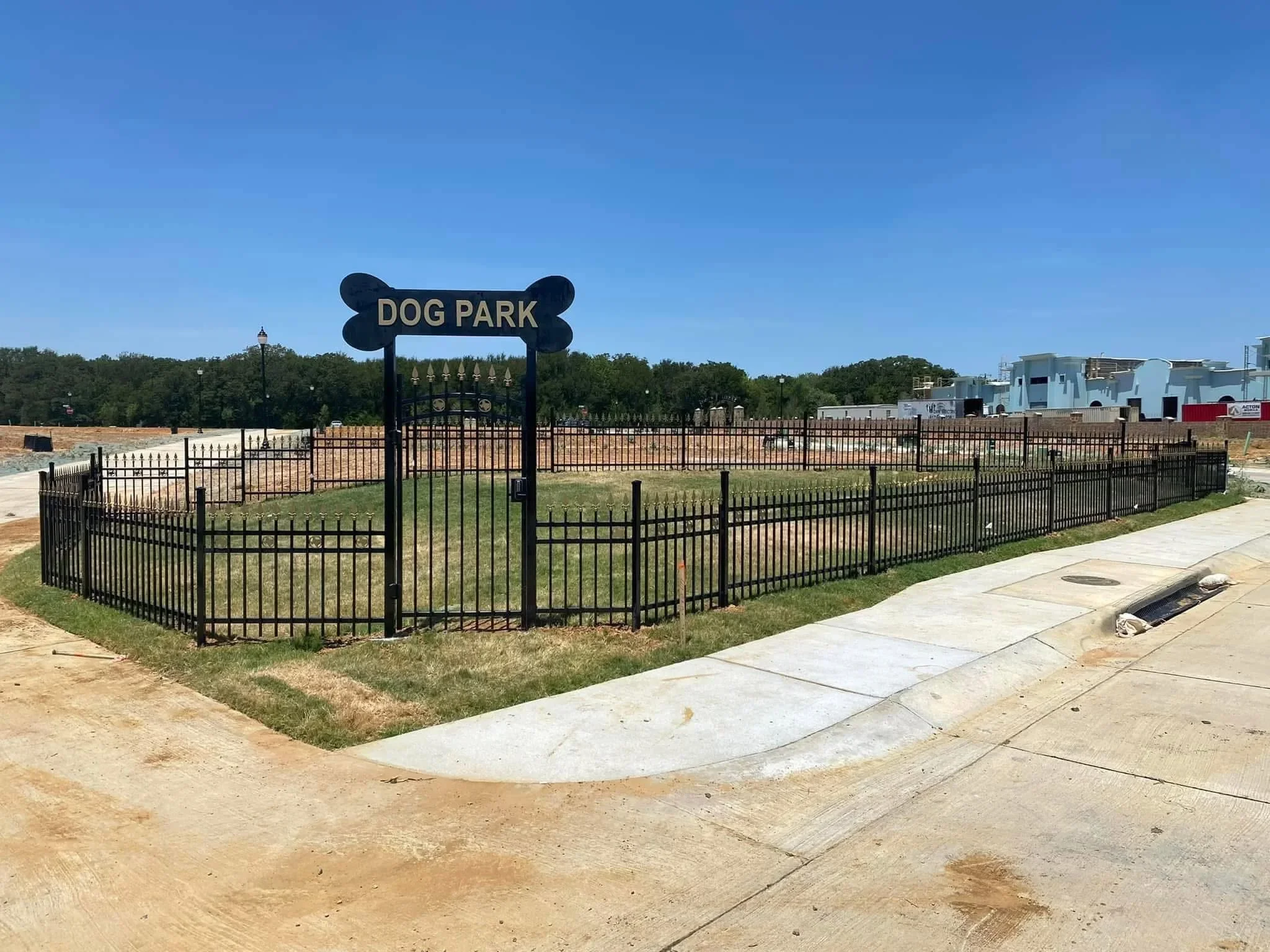 Black ornamental aluminum fence with bone-shaped gate sign around dog park enclosure