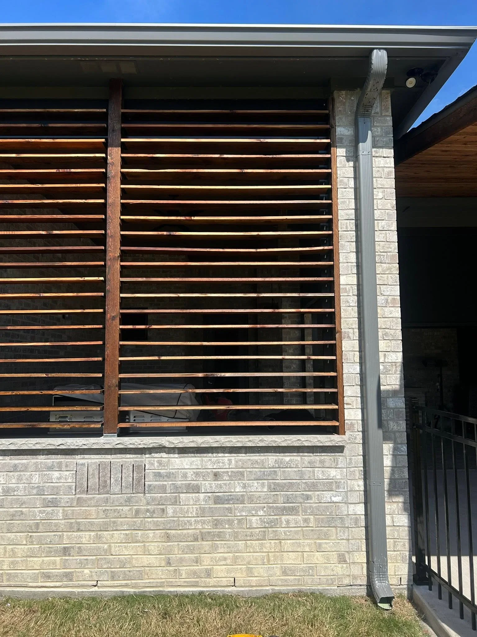 Horizontal timber slat fence with stained wood slats and steel posts on brick base