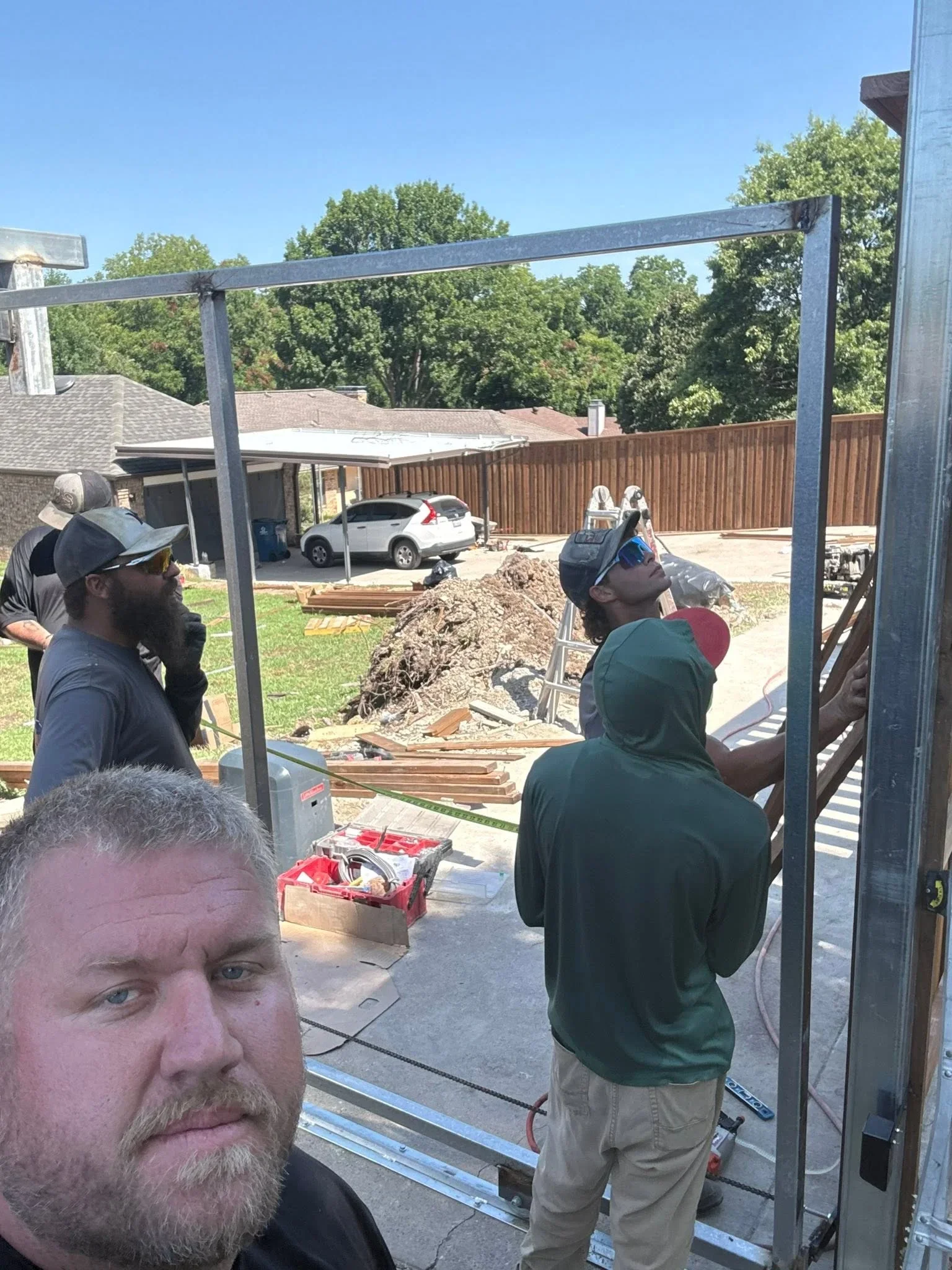 Steel pergola frame with welded posts and beams over concrete patio during installation
