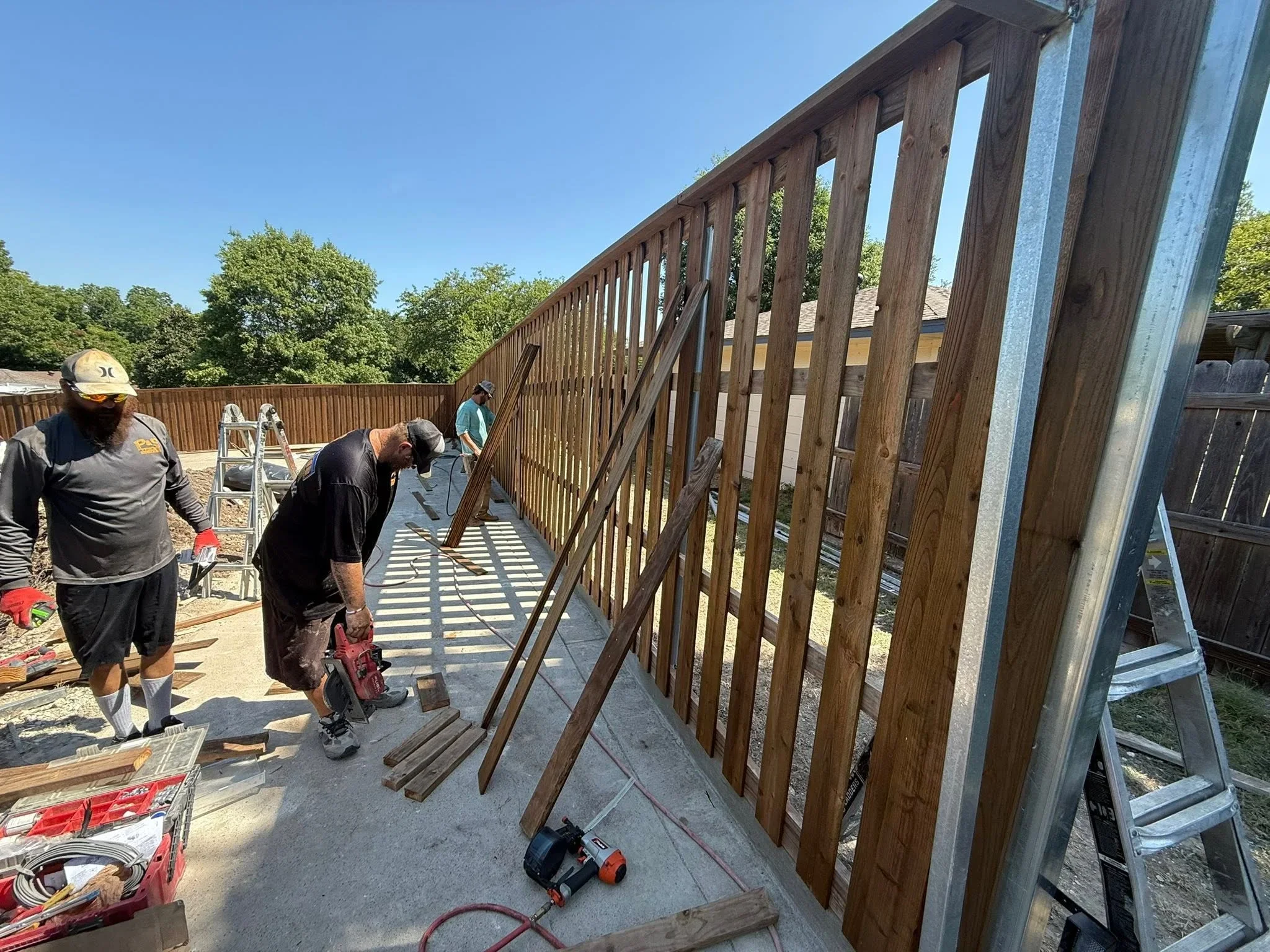 Deck framing with wooden vertical spindle railing under construction on concrete foundation