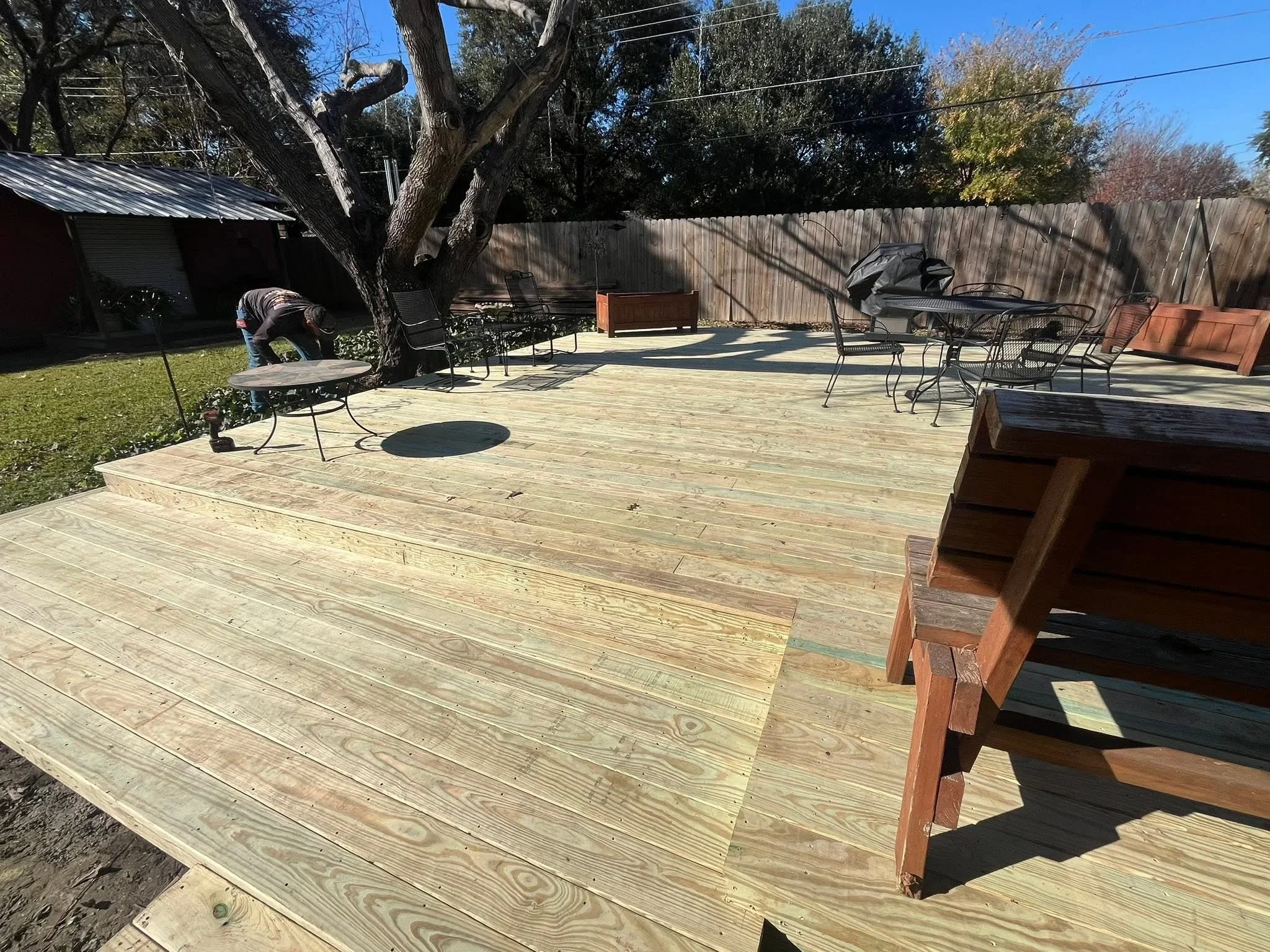 Pressure-treated wood deck with multi-level construction and wooden steps in residential backyard