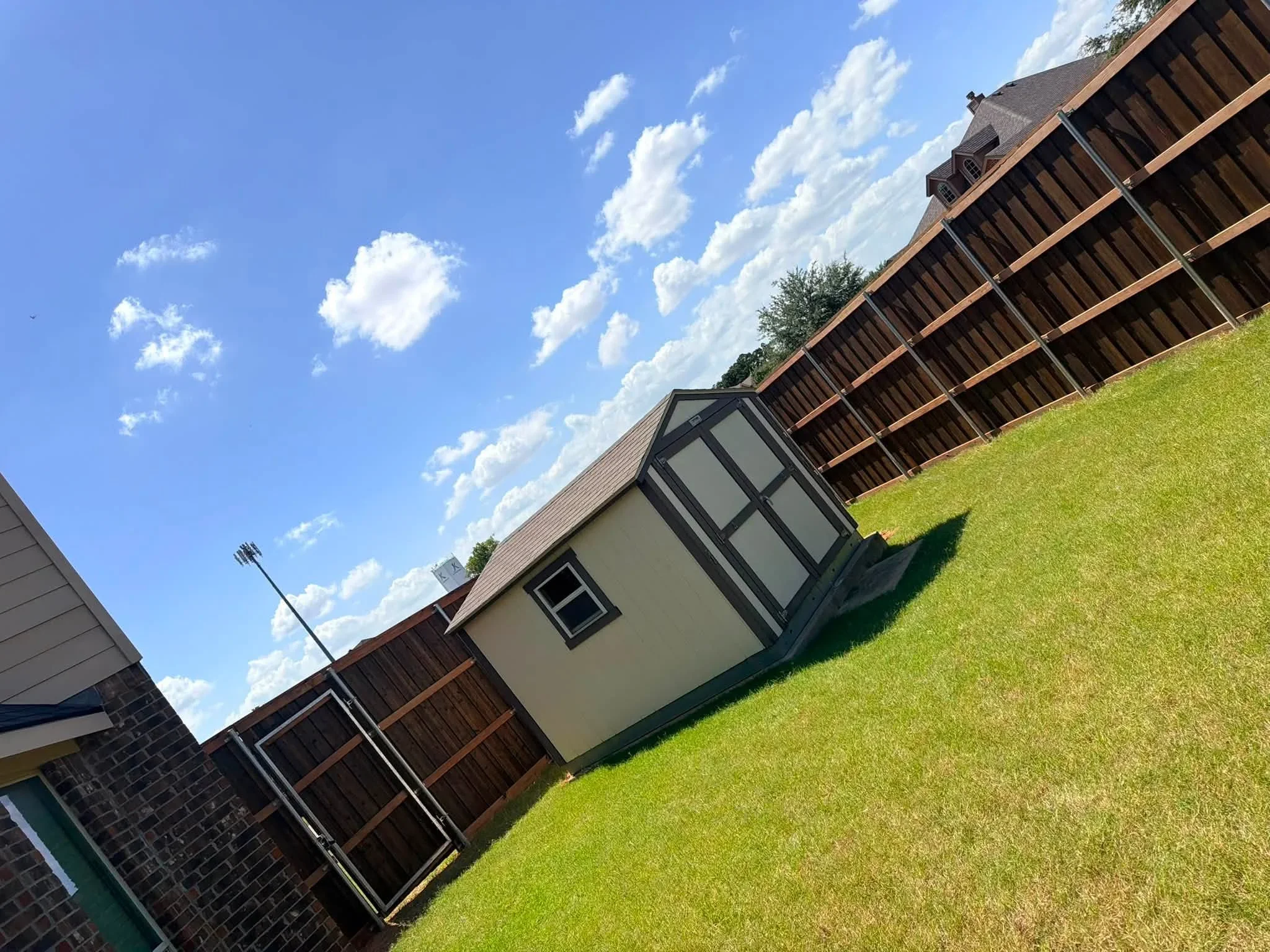 Stained cedar wood fence with black metal posts and framework along residential lawn