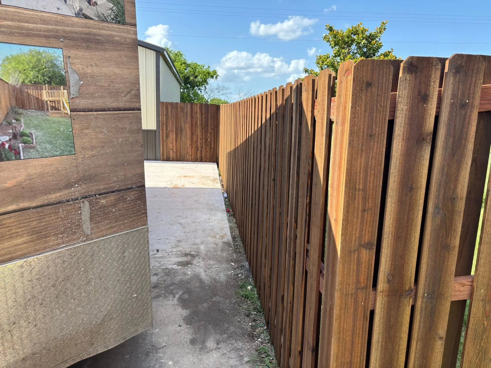 Vertical wood privacy fence with natural stain, installed along residential property line