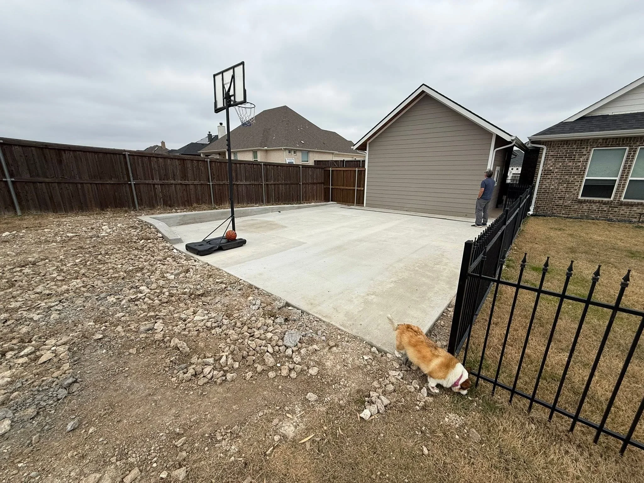 Concrete pad with wooden privacy fence and metal decorative fencing in residential backyard