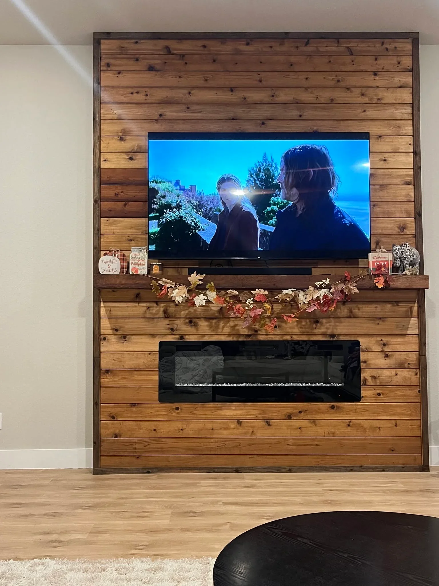 Reclaimed wood shiplap feature wall with mounted TV and black electric fireplace insert
