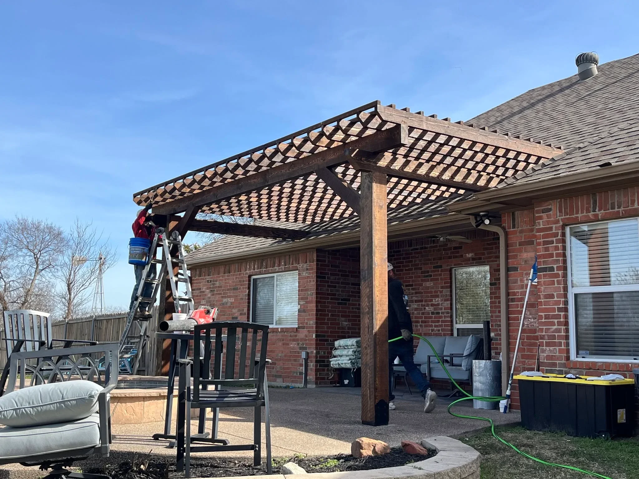 Wooden pergola with lattice panels and timber posts over brick patio