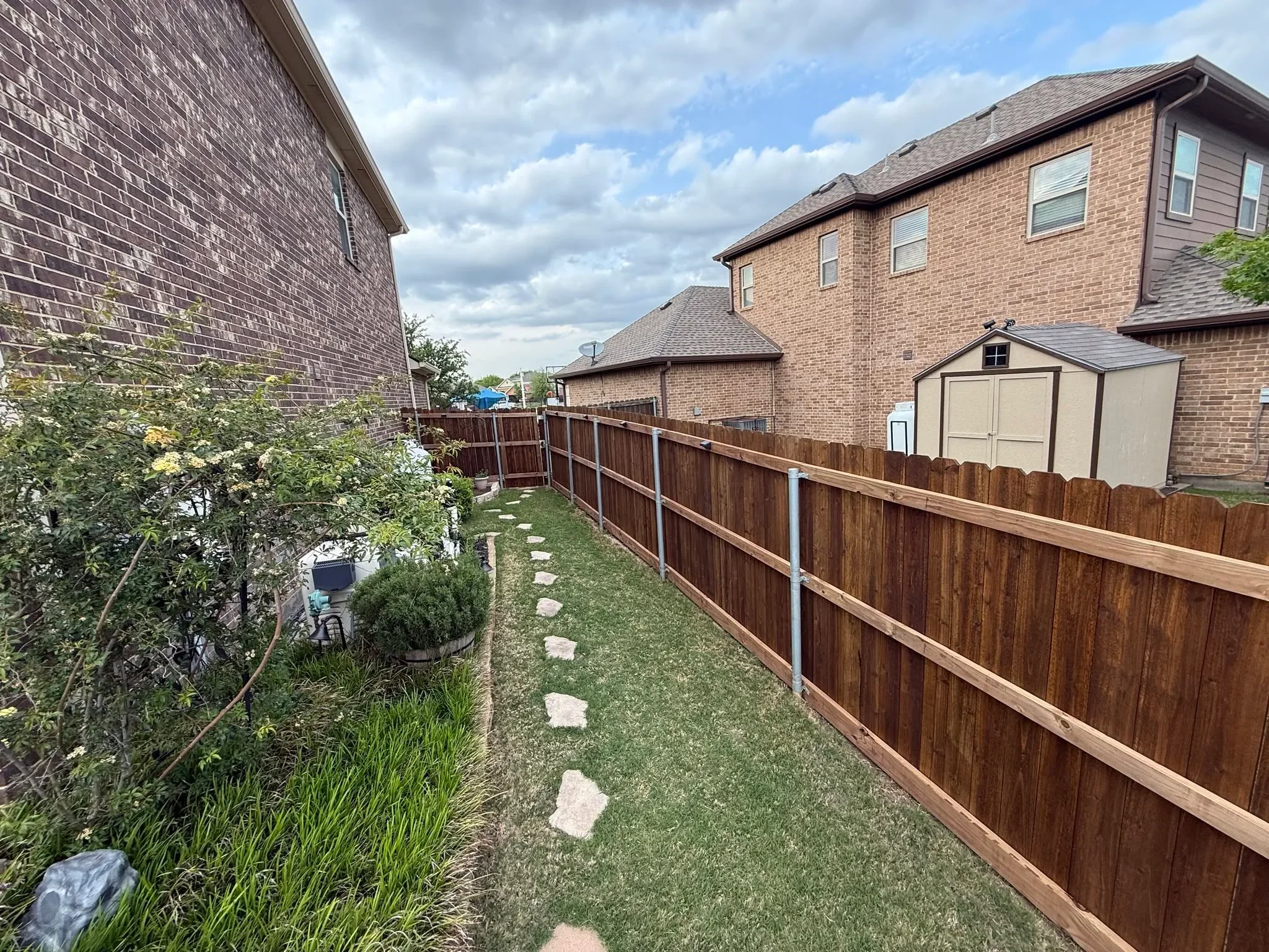 Stained cedar wood privacy fence with metal posts installed along residential side yard