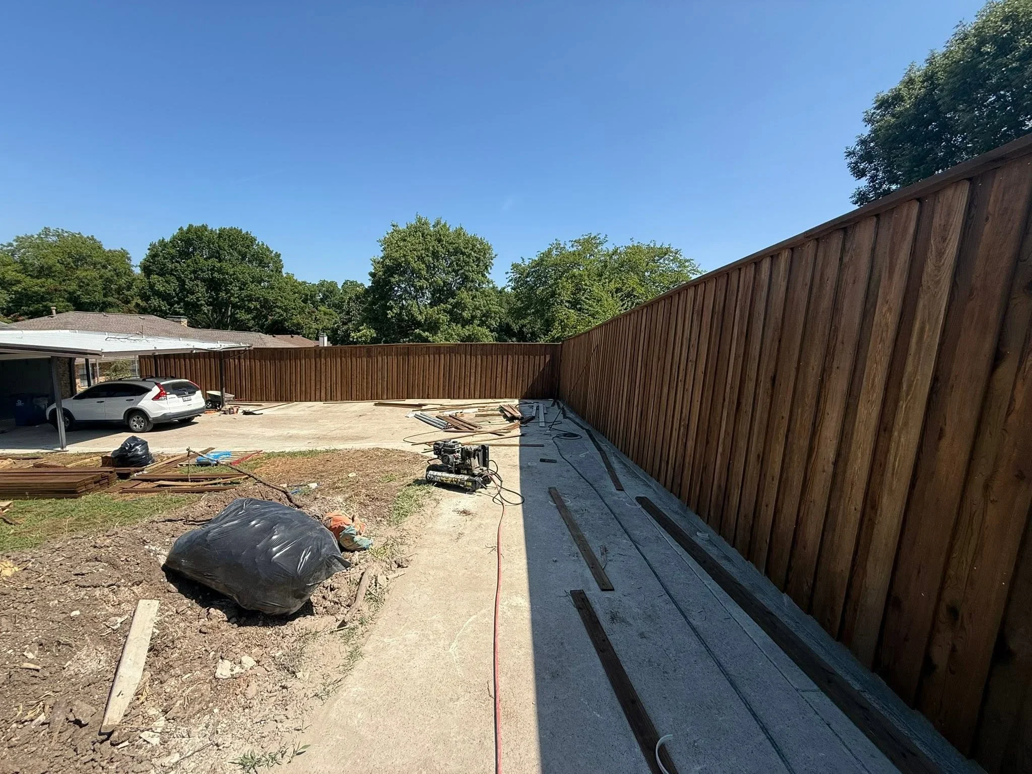 Tall corrugated metal privacy fence with brown panels installed around residential backyard