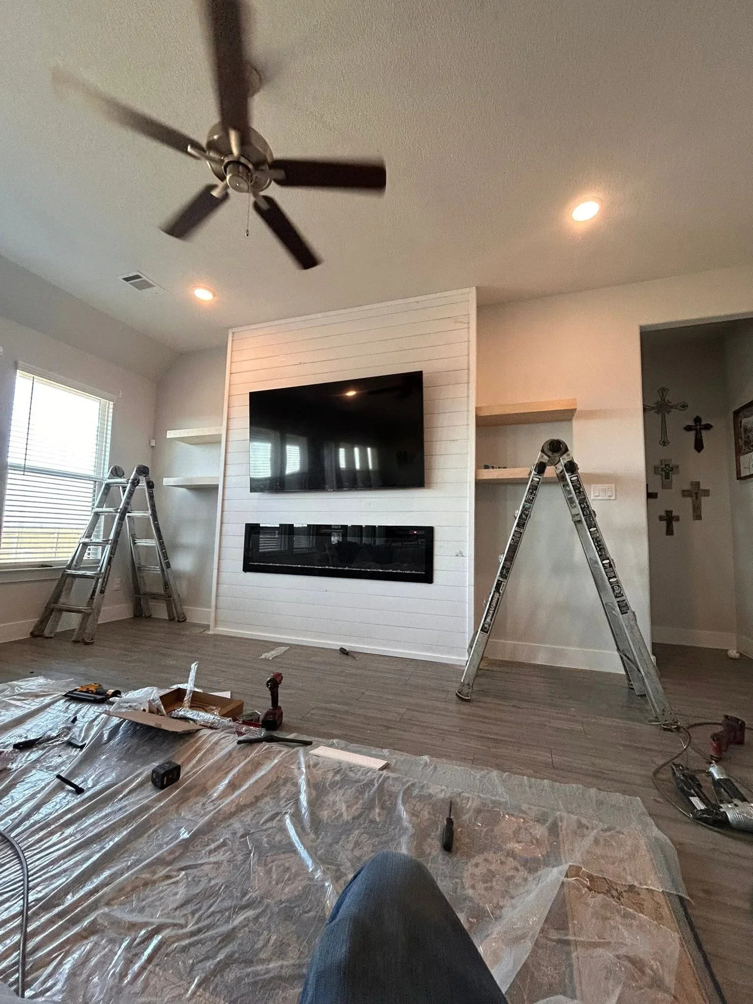 White shiplap fireplace wall with black linear insert and built-in shelves under construction