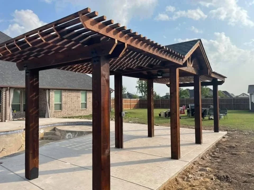 Stained wood pergola with lattice roof over concrete patio and hot tub area