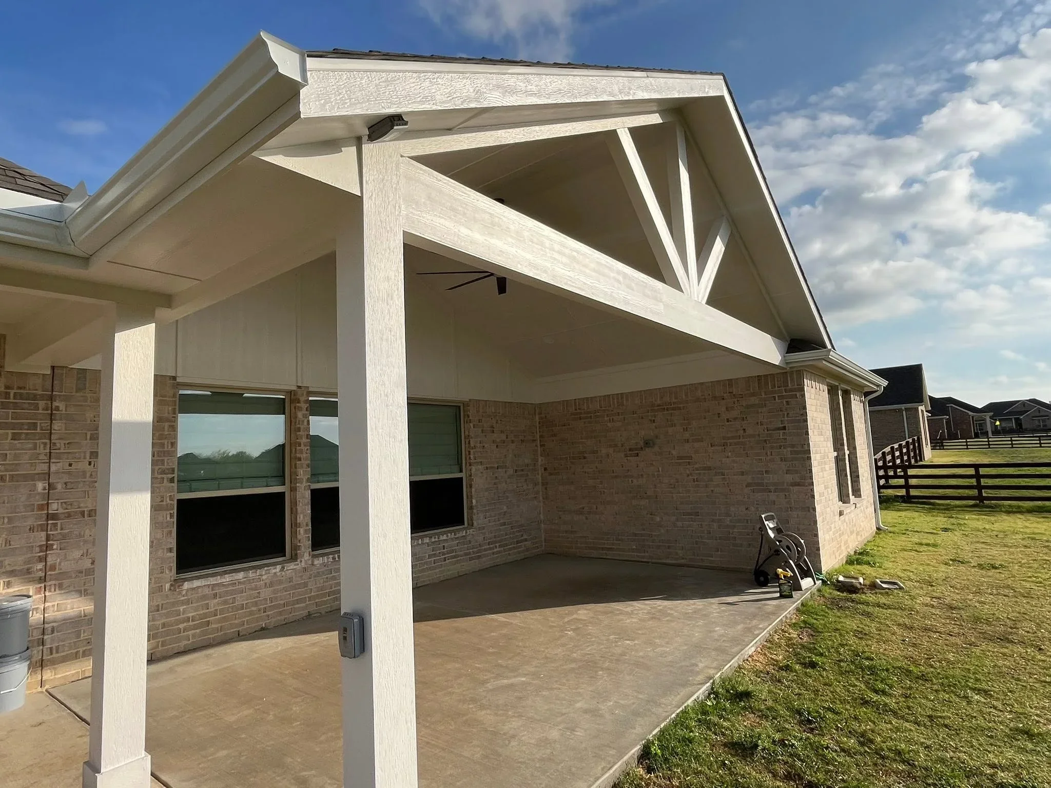 Whitewashed wood pergola patio cover with decorative bracing over concrete pad