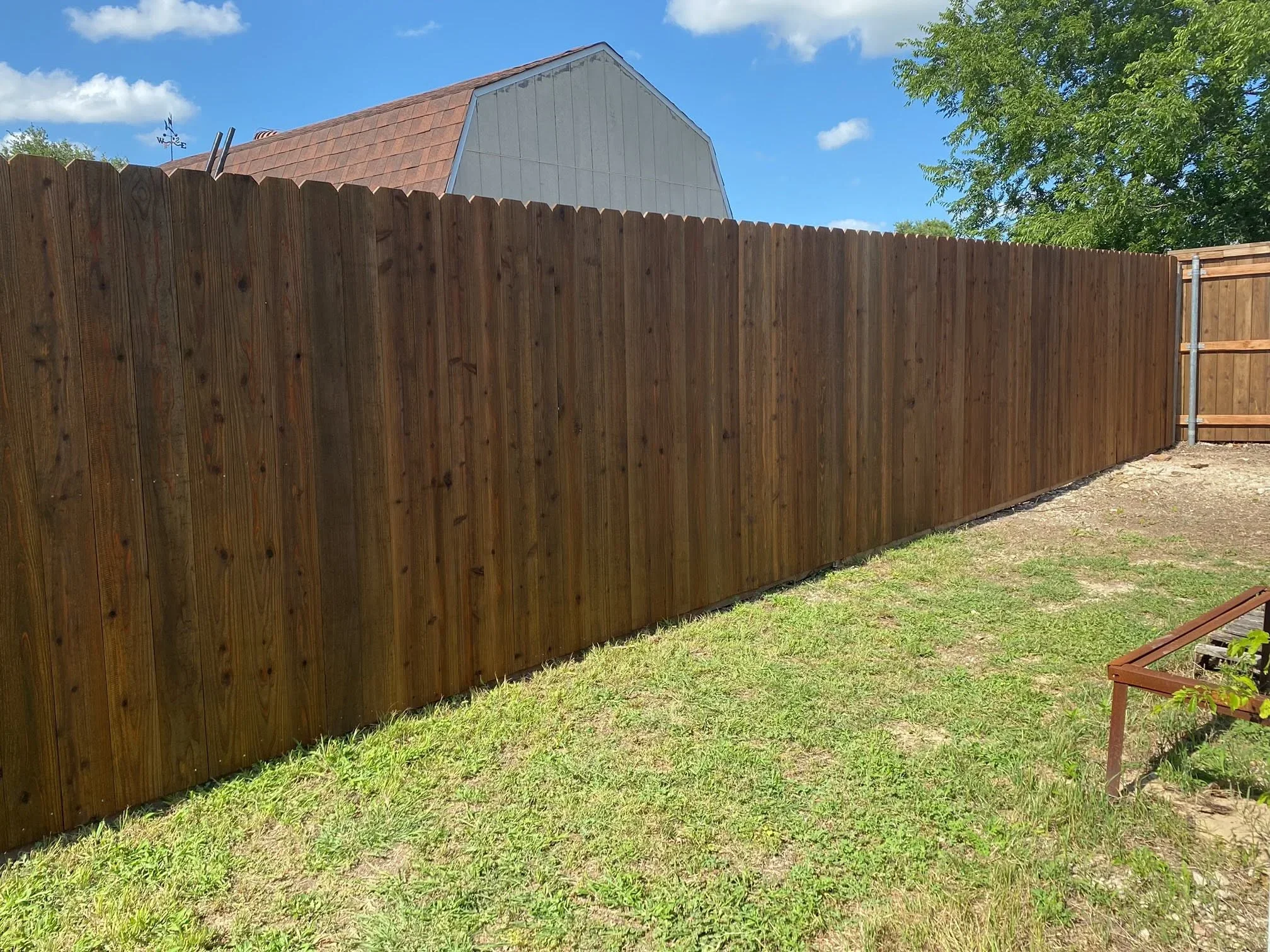 Stained wood privacy fence with vertical boards installed along residential property line