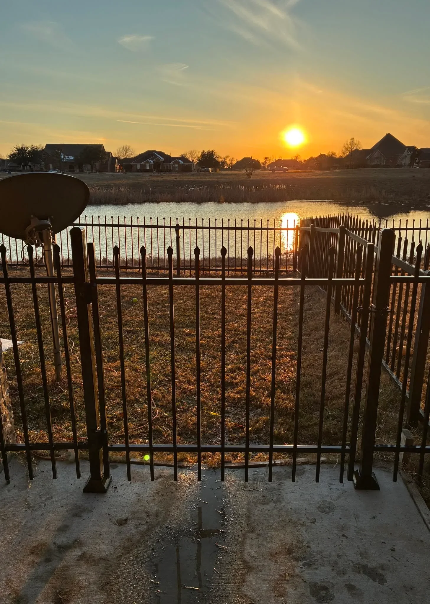 Black ornamental iron fence with spear-top pickets and gate at waterfront property