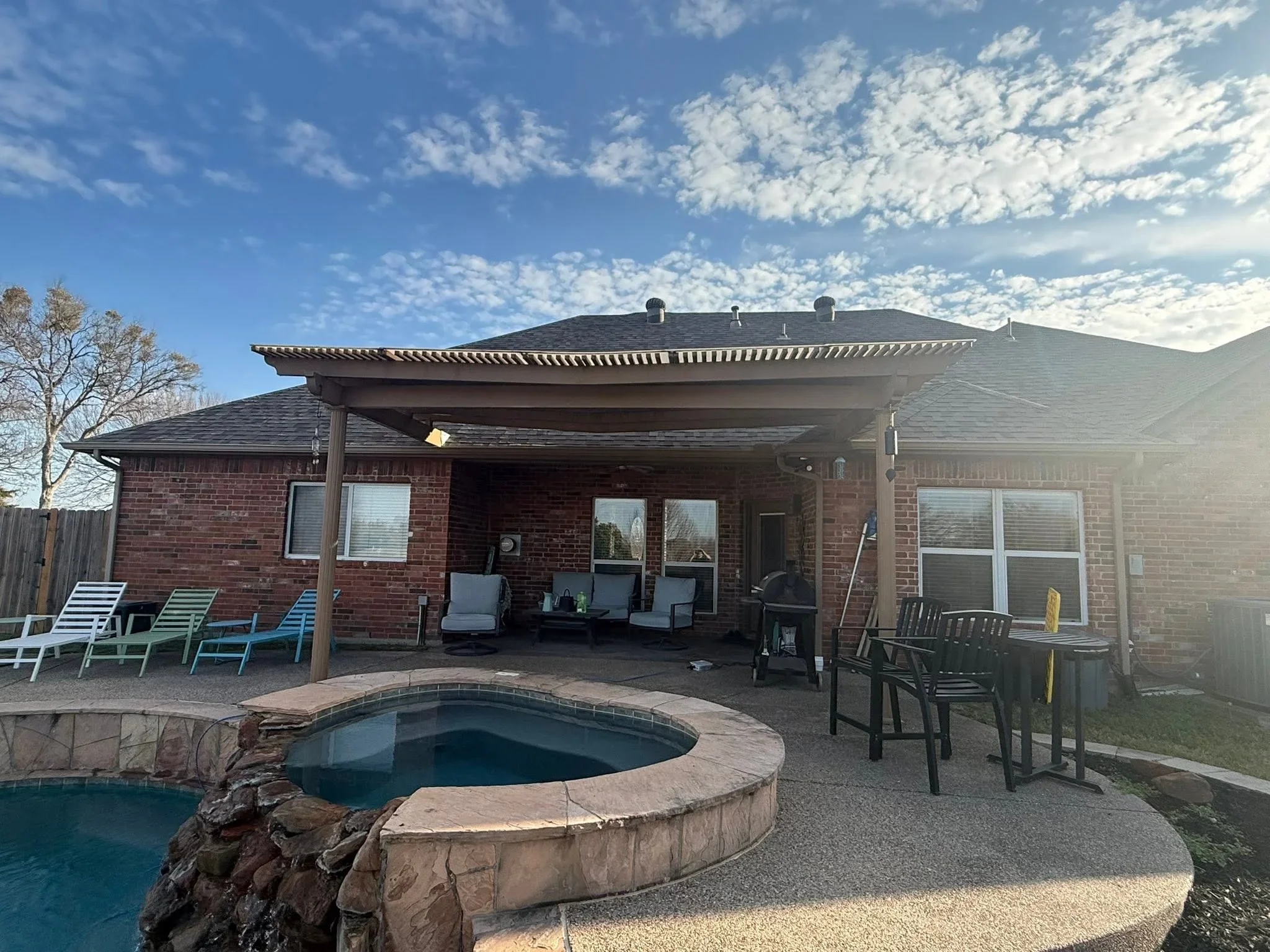 Slatted pergola shade structure over patio with pool and spa in foreground