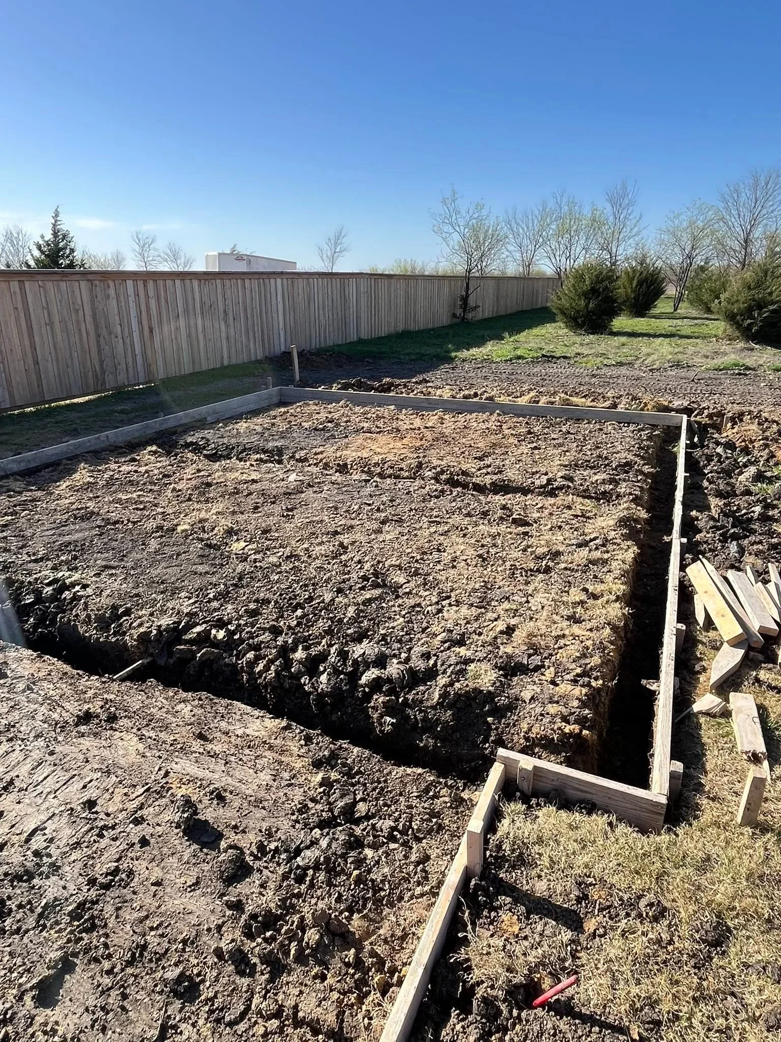 Metal corrugated fence with wooden frame and concrete footings installed along property line