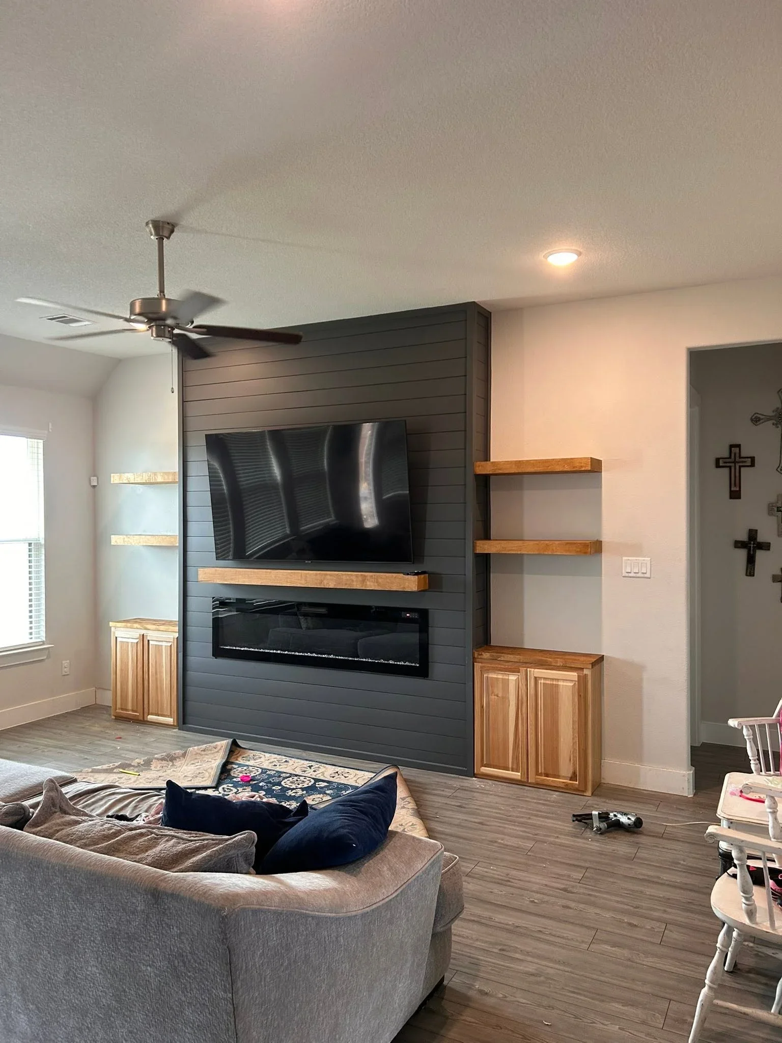 Charcoal shiplap entertainment wall with electric fireplace, TV mount, wood shelves and cabinets