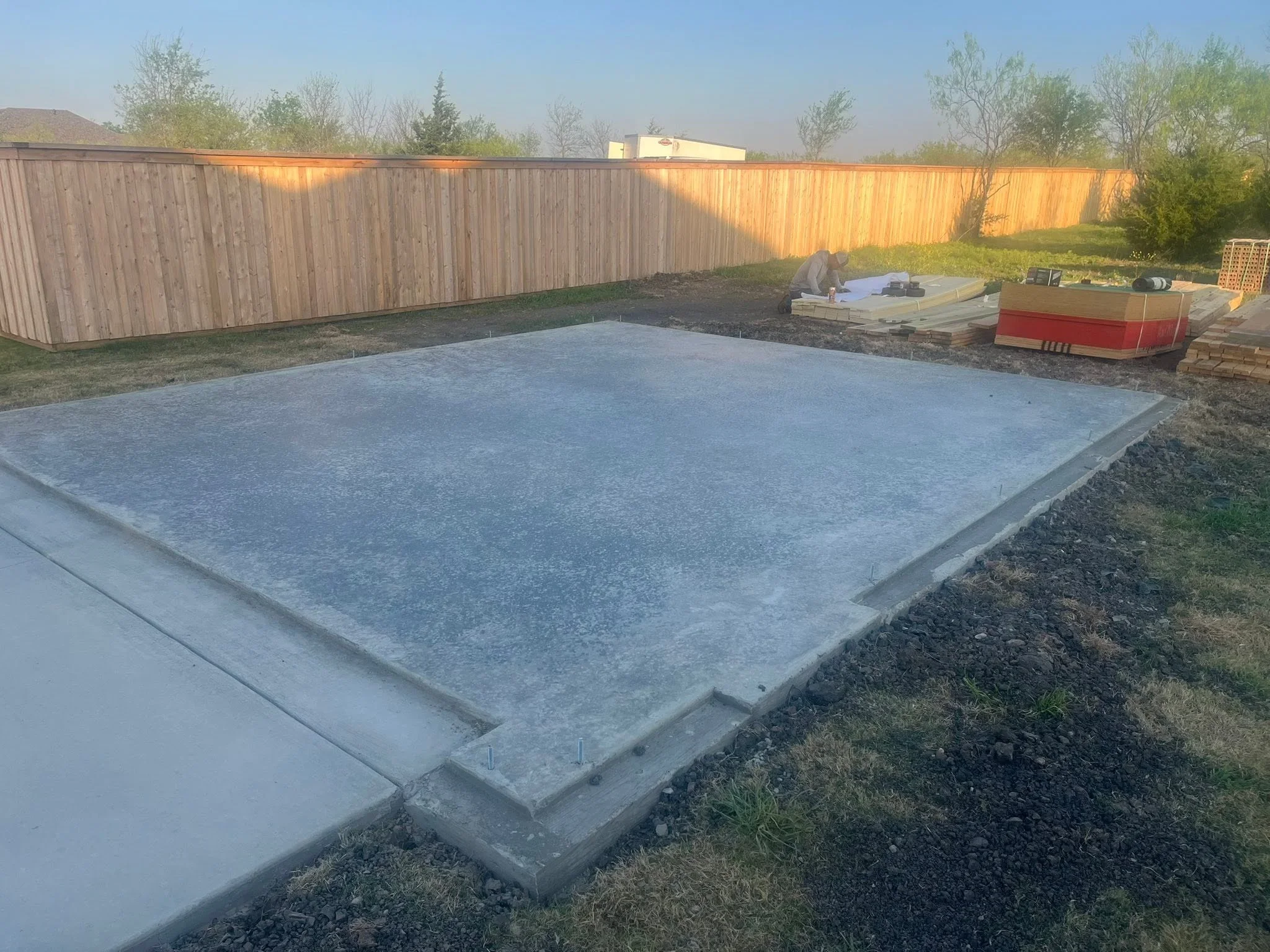 Finished concrete pad with formed edges in fenced residential yard