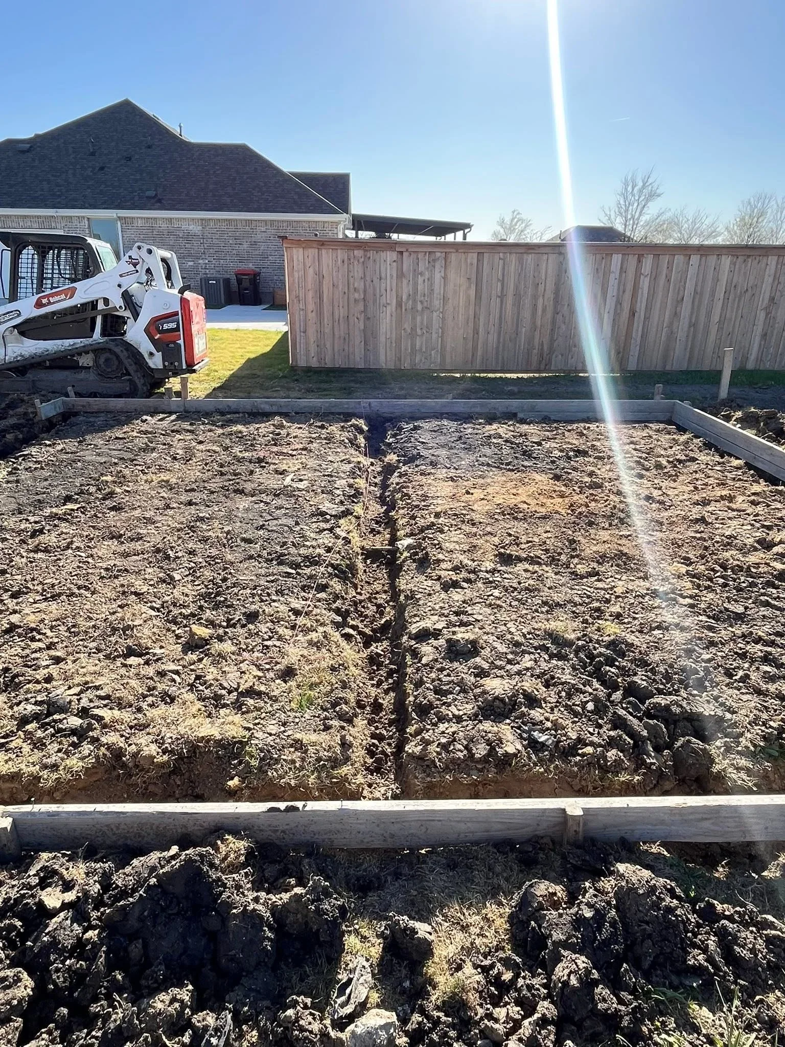 Wooden privacy fence with concrete foundation posts and gravel base during installation
