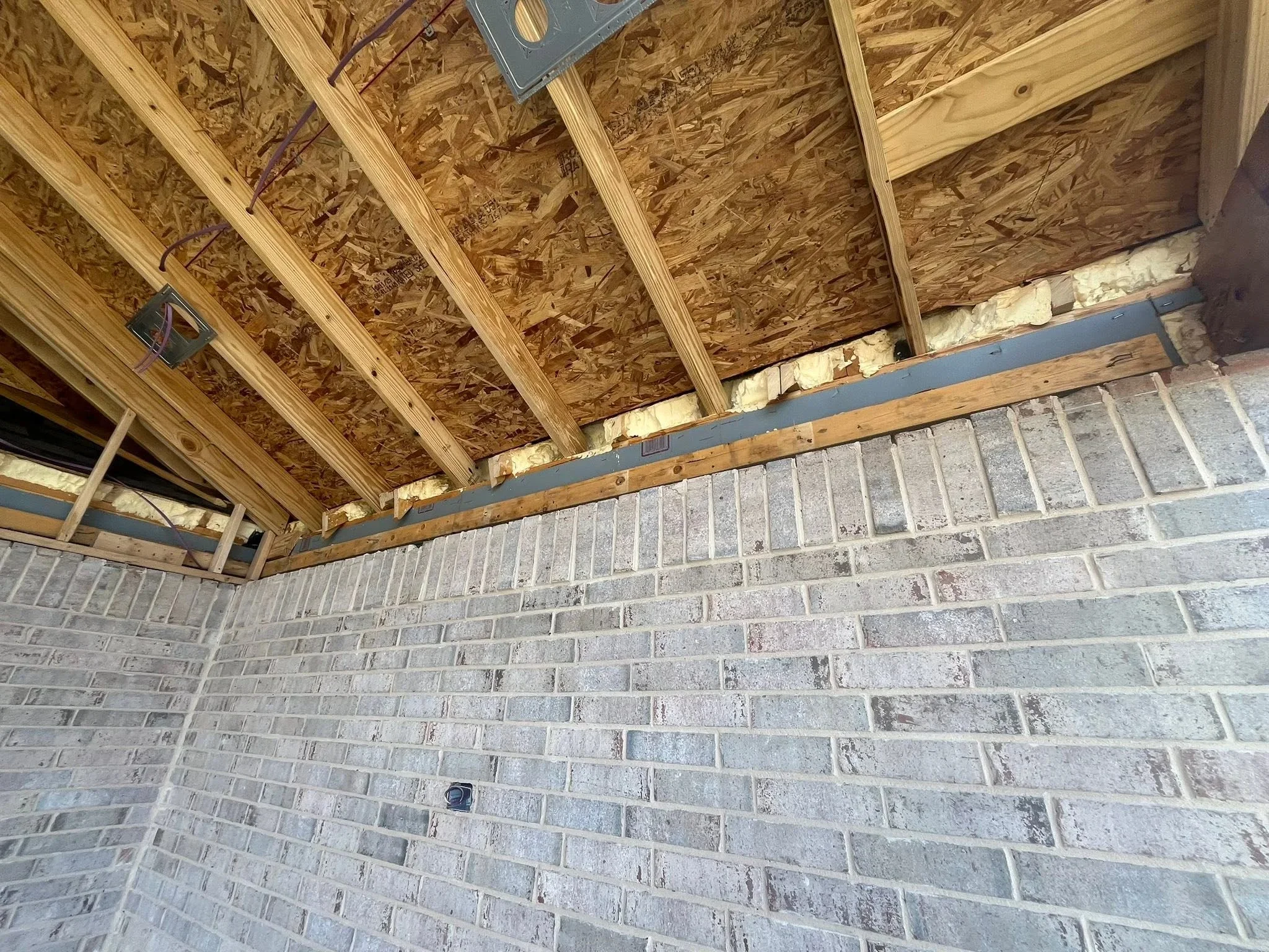 OSB soffit sheathing with metal fascia trim and electrical conduit under construction