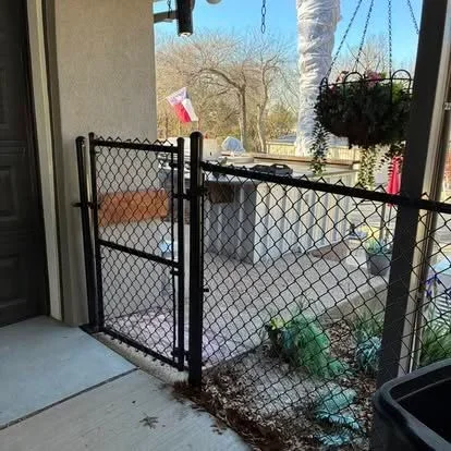 Black chain link gate with self-closing hinge mounted at patio entrance