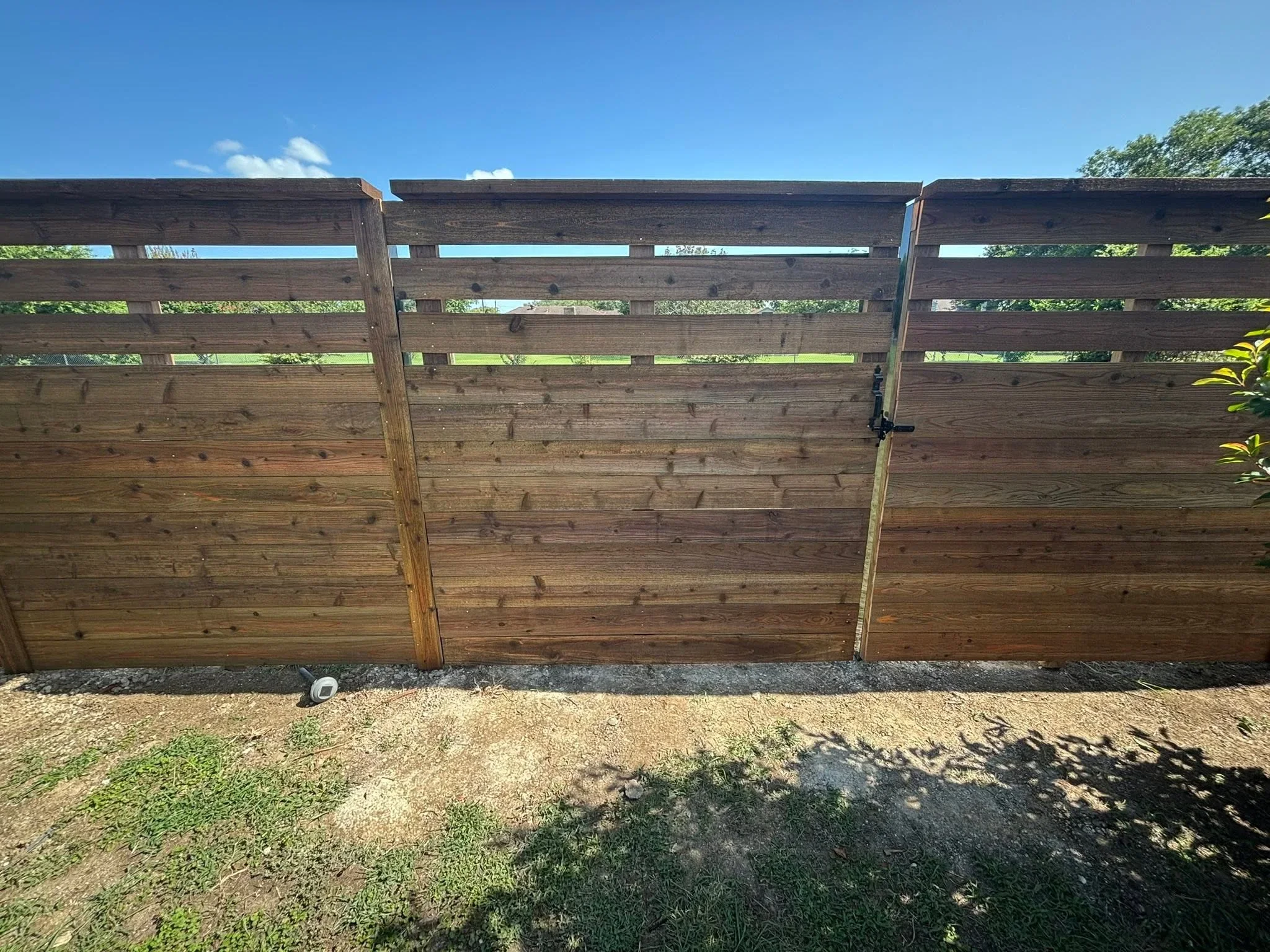Horizontal wood driveway gate with open lattice top and solid lower panels