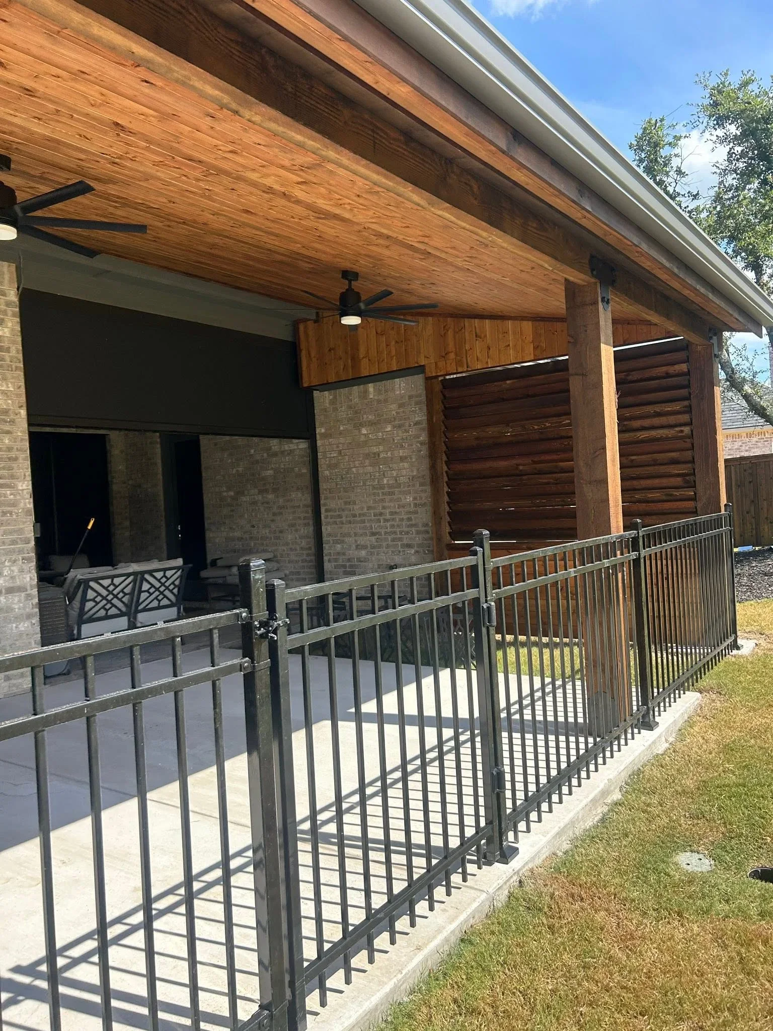 Aluminum metal railing with vertical balusters on composite deck, gate opening visible