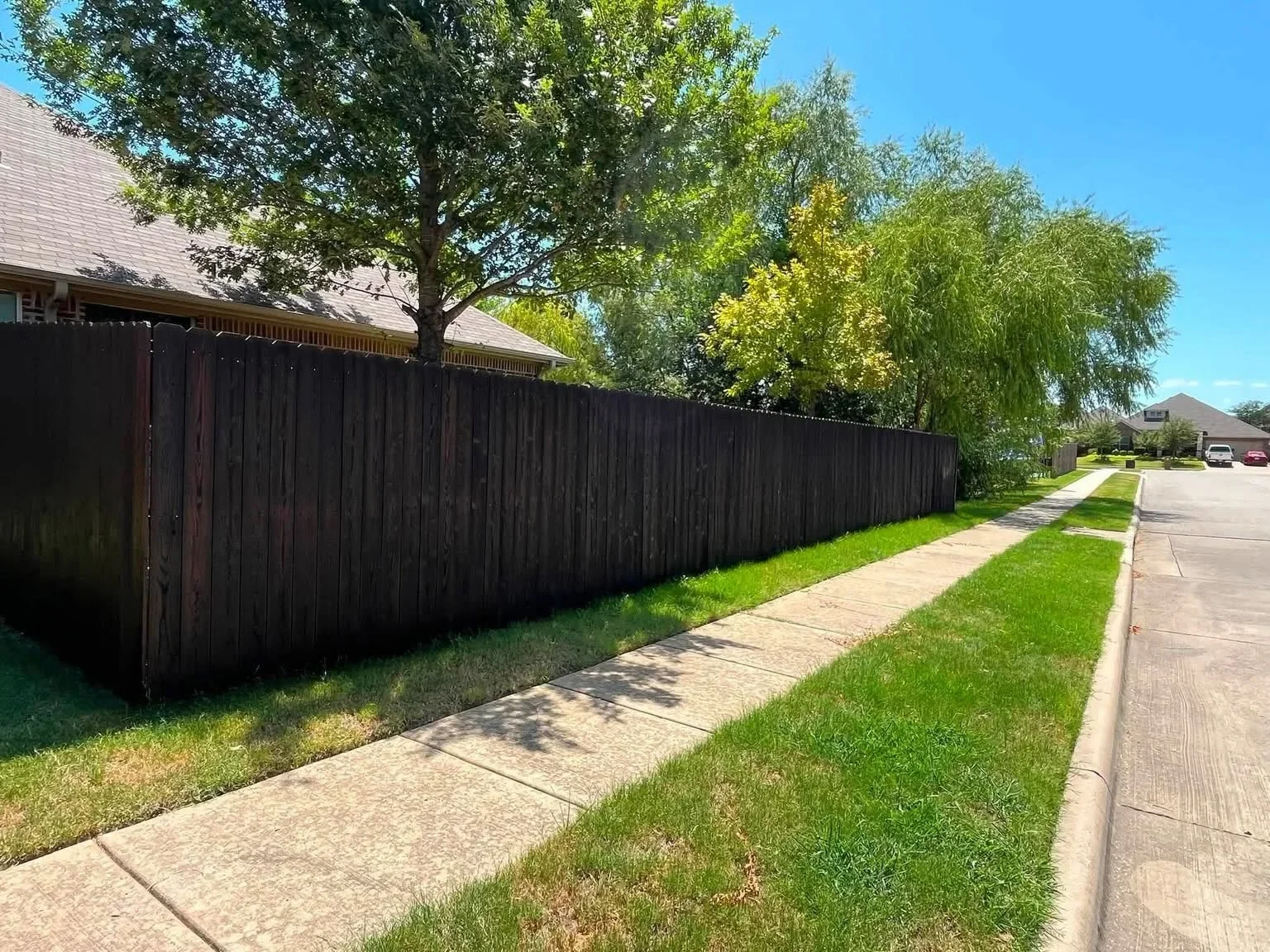 Dark stained wood privacy fence with vertical planks along residential property line