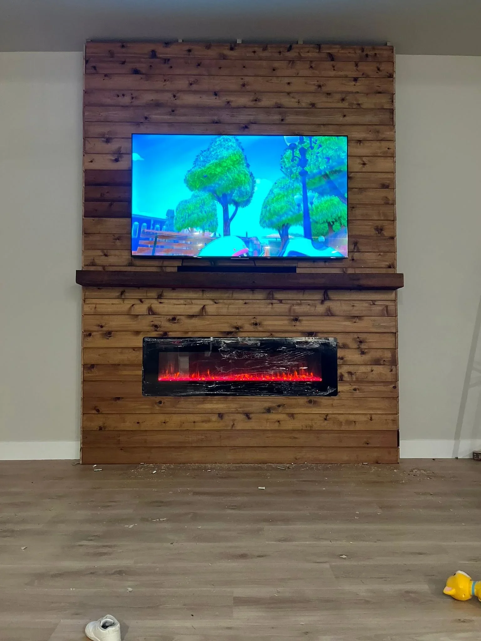 Horizontal knotty pine shiplap wall with mounted TV and electric fireplace insert