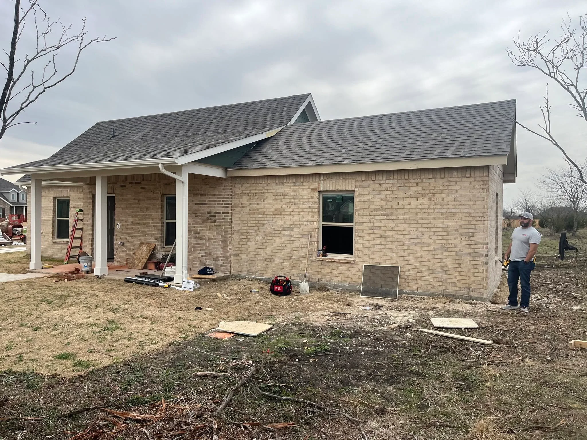 Brick residential home under construction with white covered porch and composite deck framing