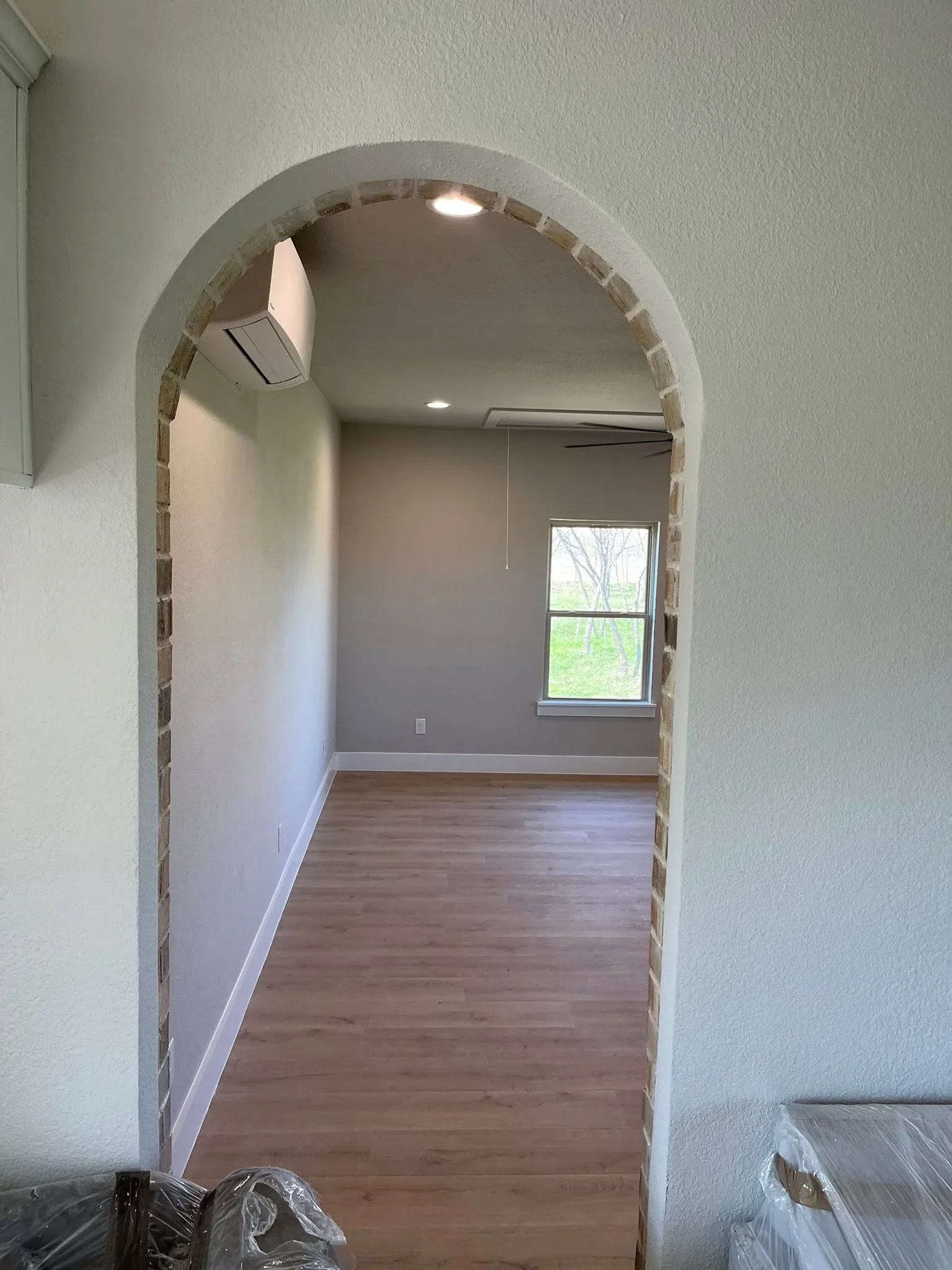 Arched brick entryway with recessed lighting and finished drywall interior