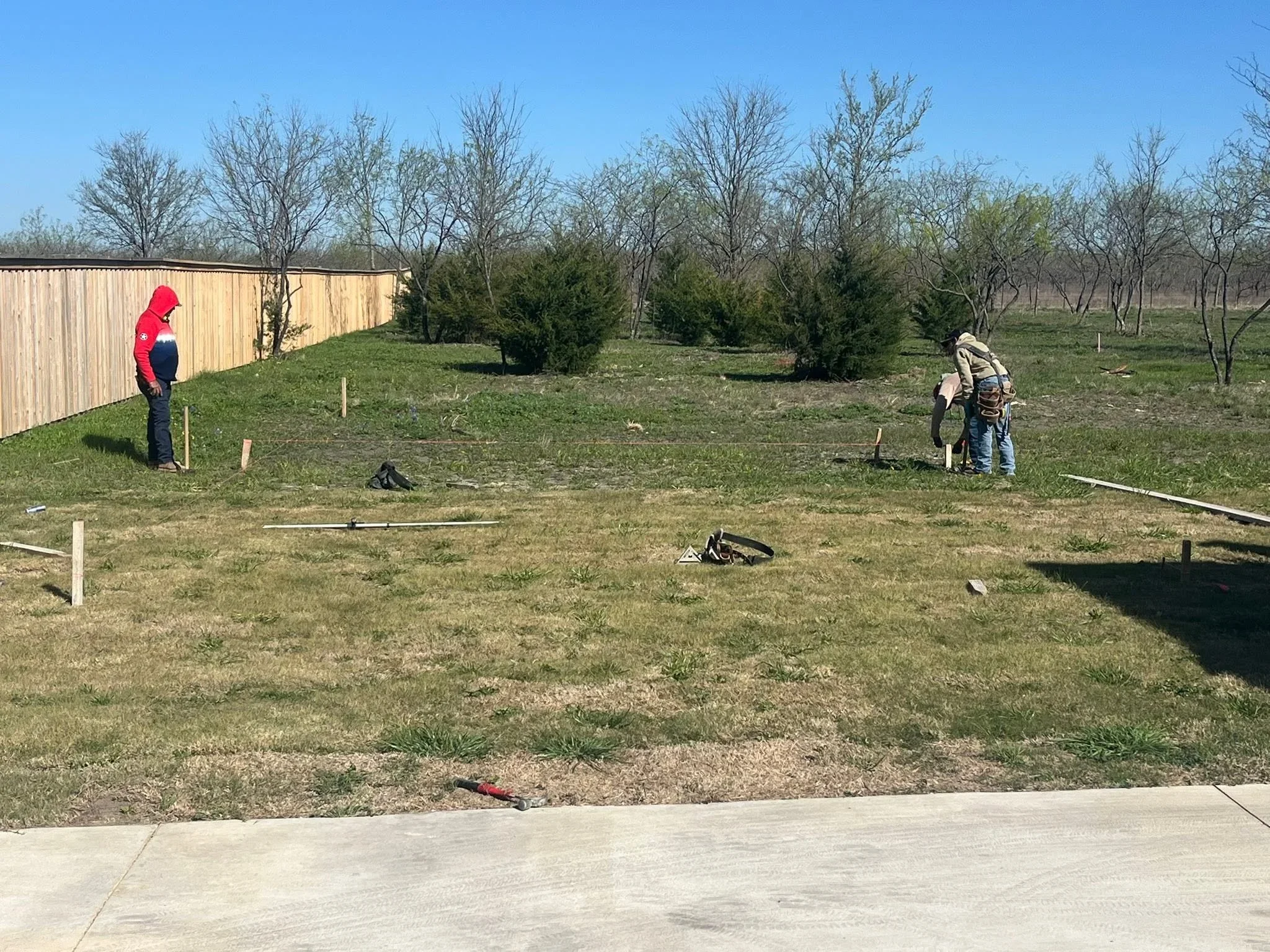 Corrugated metal fence installation with wooden posts and stakes marking property line