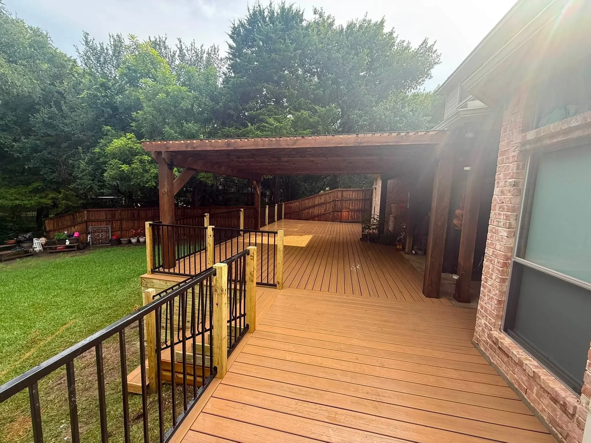 Composite deck with pergola, metal railings, and multi-level design attached to brick home