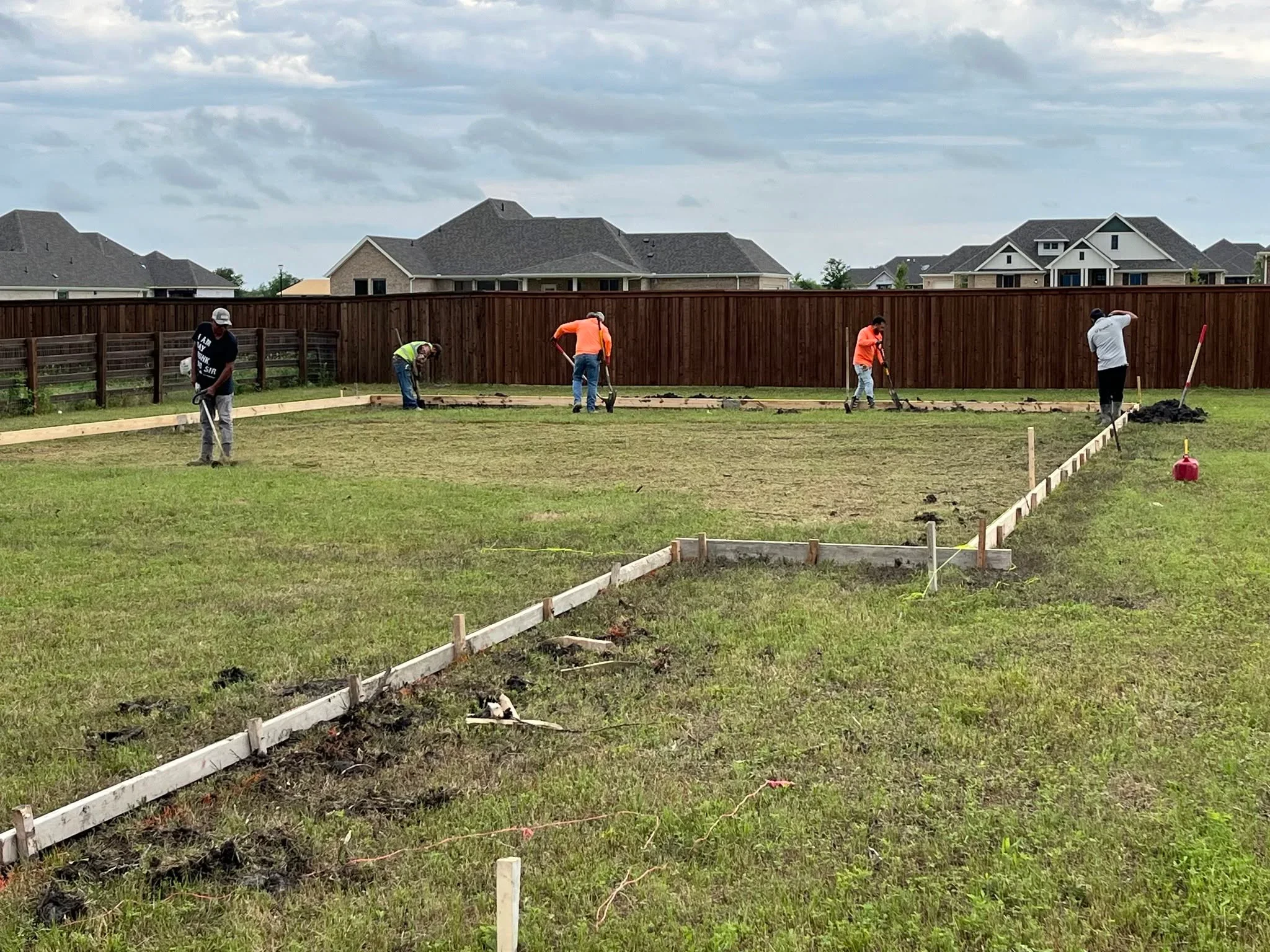 Dark wood privacy fence installation with white trim edging and concrete footings in residential yard