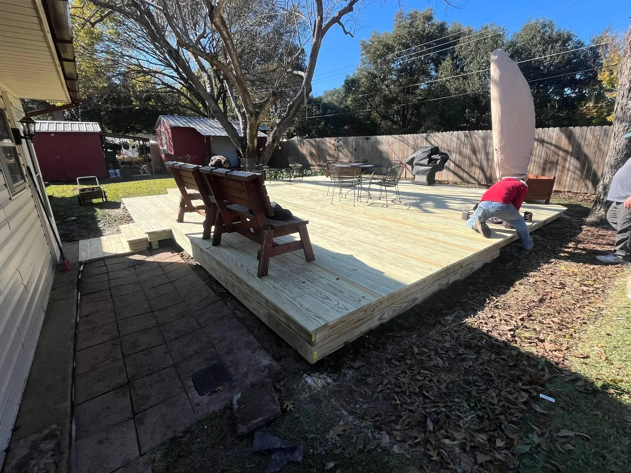 Newly constructed pressure-treated wood deck with framing visible, elevated platform in residential backyard
