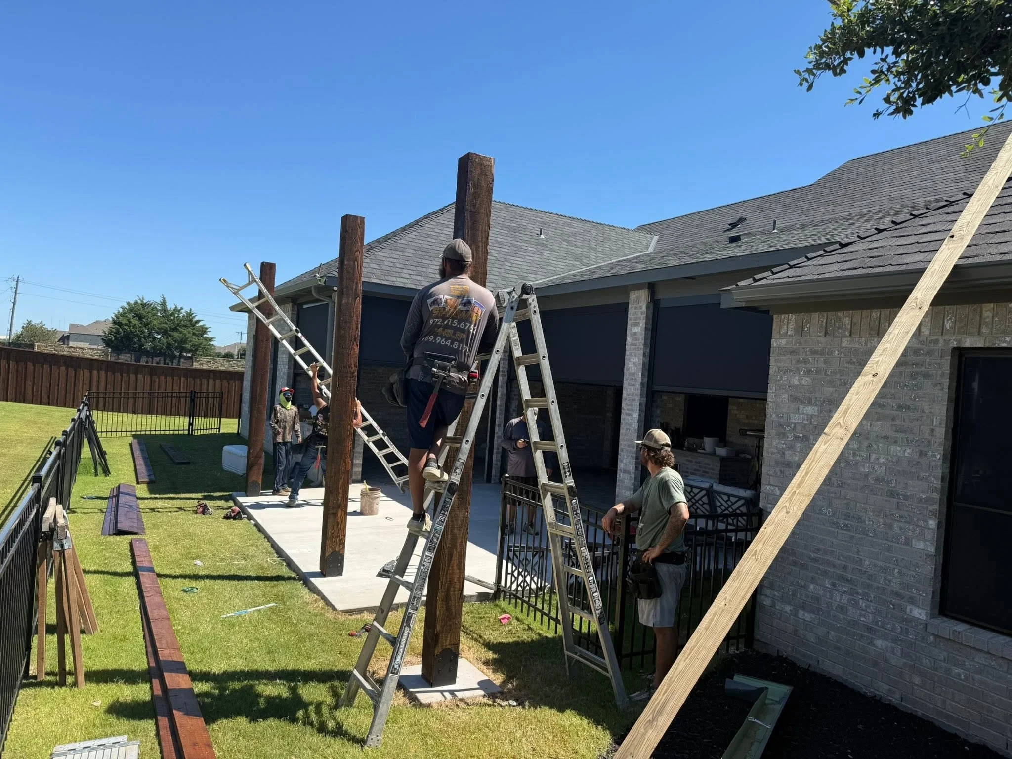 Wooden pergola with timber posts and metal railings over concrete patio during installation