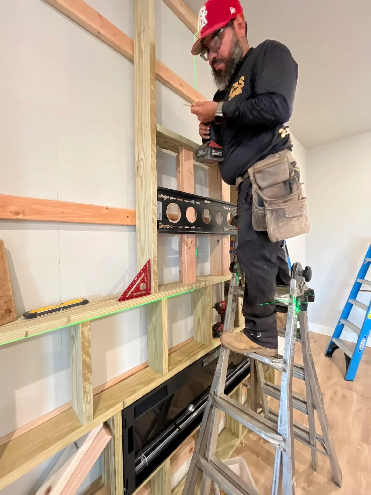 Carpenter installing wood-framed kitchen cabinets with glass doors and stained wood finish