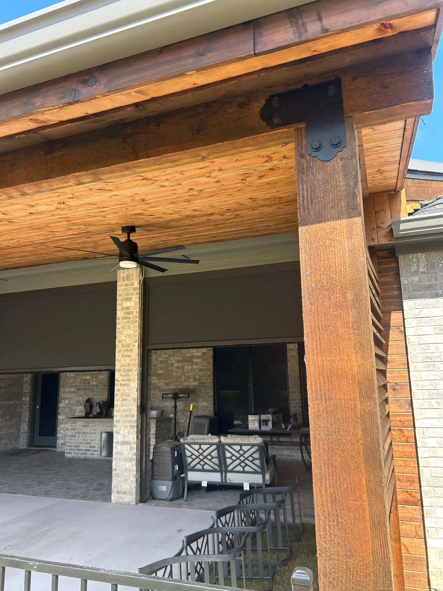 Covered patio with timber beams, brick columns, sliding glass doors, and ceiling fan