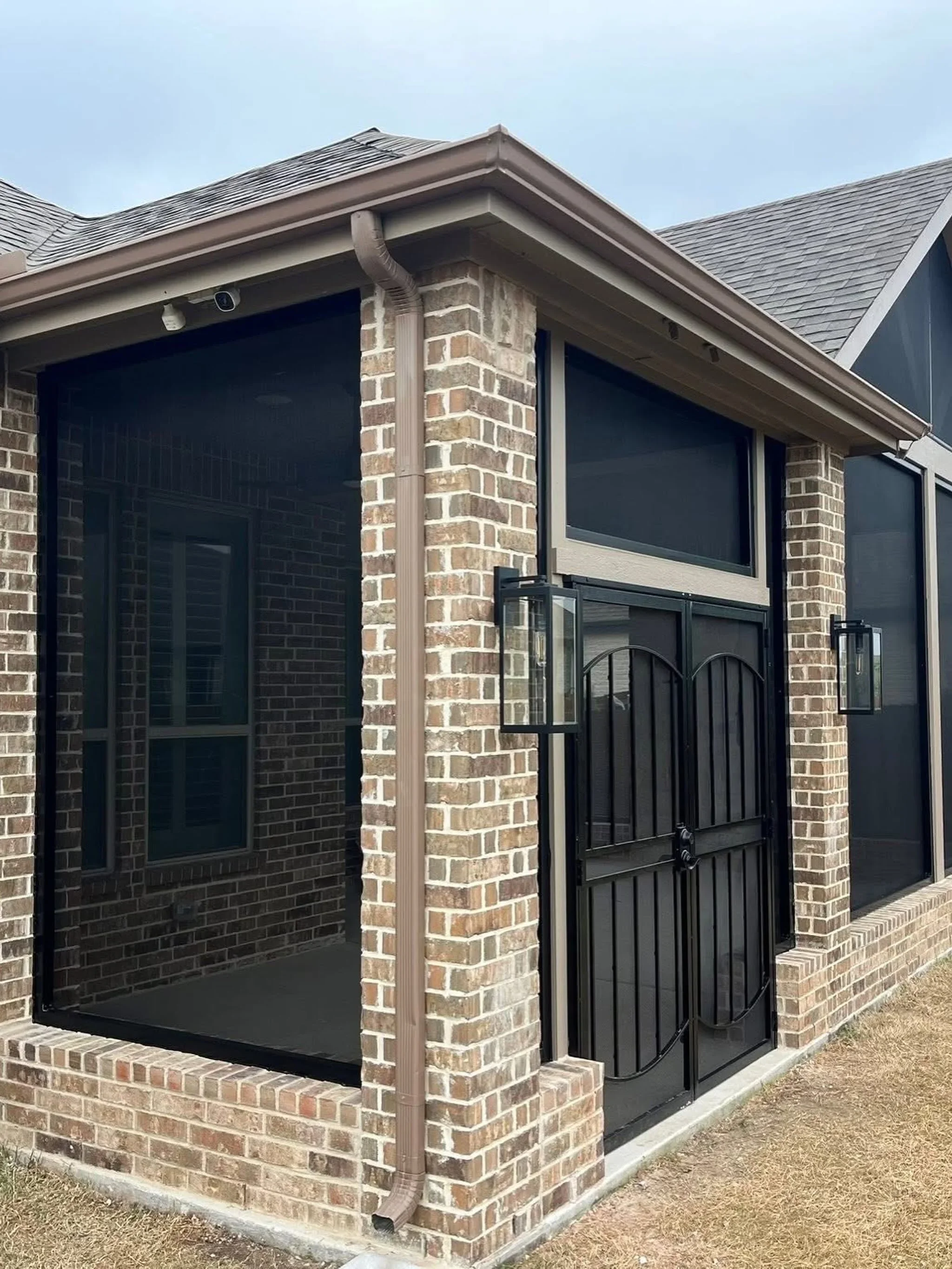 Black steel dual gates with vertical bar railing on brick porch entrance