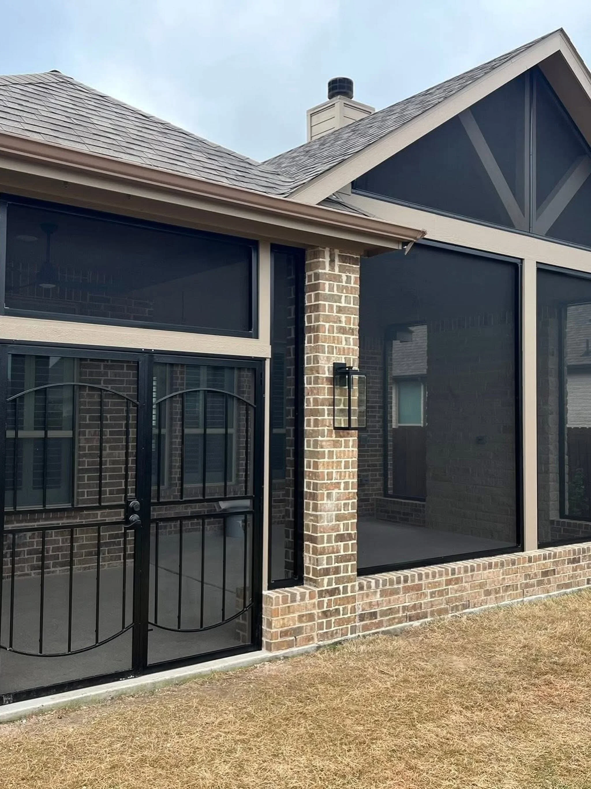 Black aluminum screened patio with metal railing and brick chimney detail