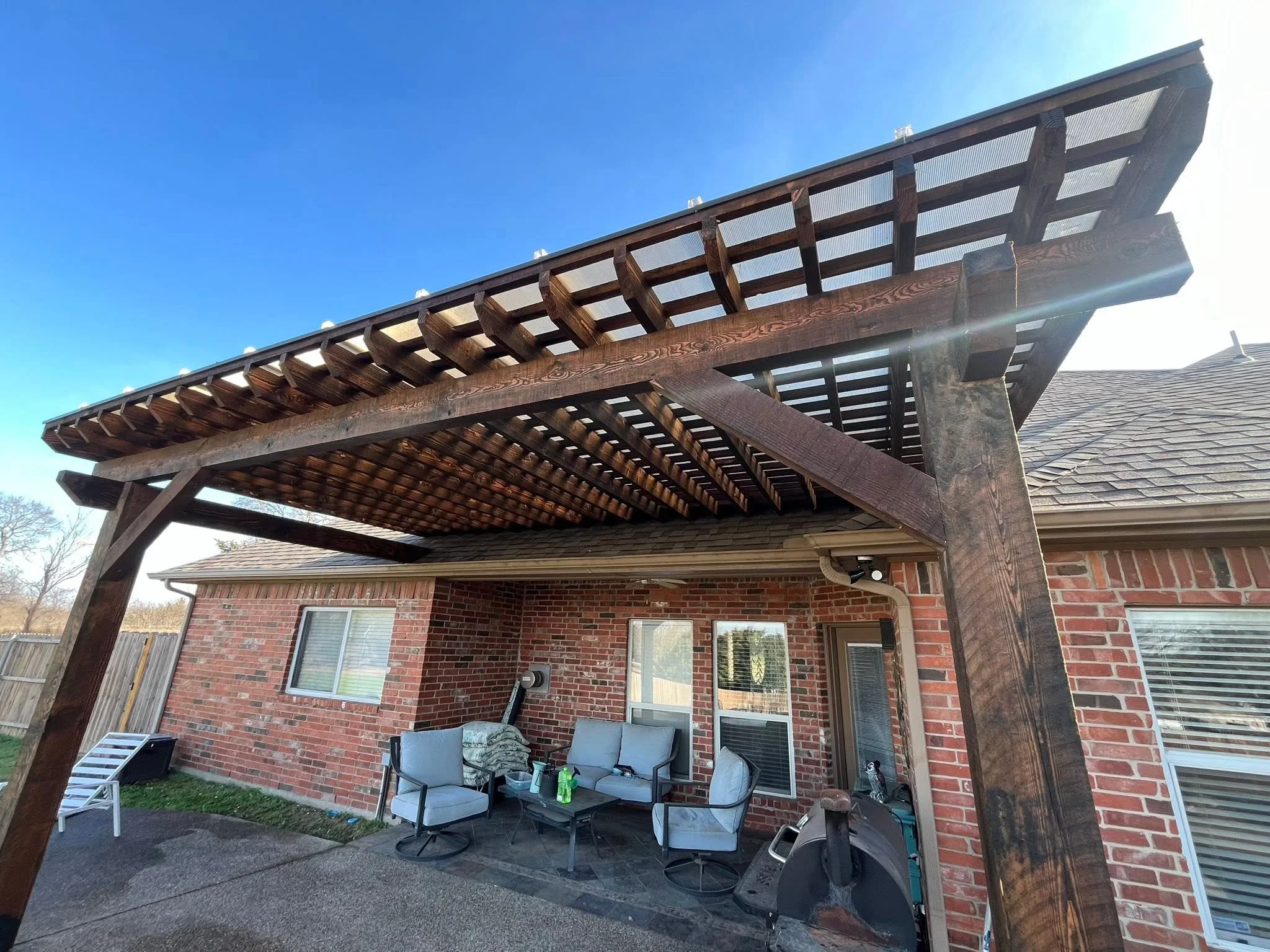 Stained wood pergola with lattice panels over brick patio and seating area
