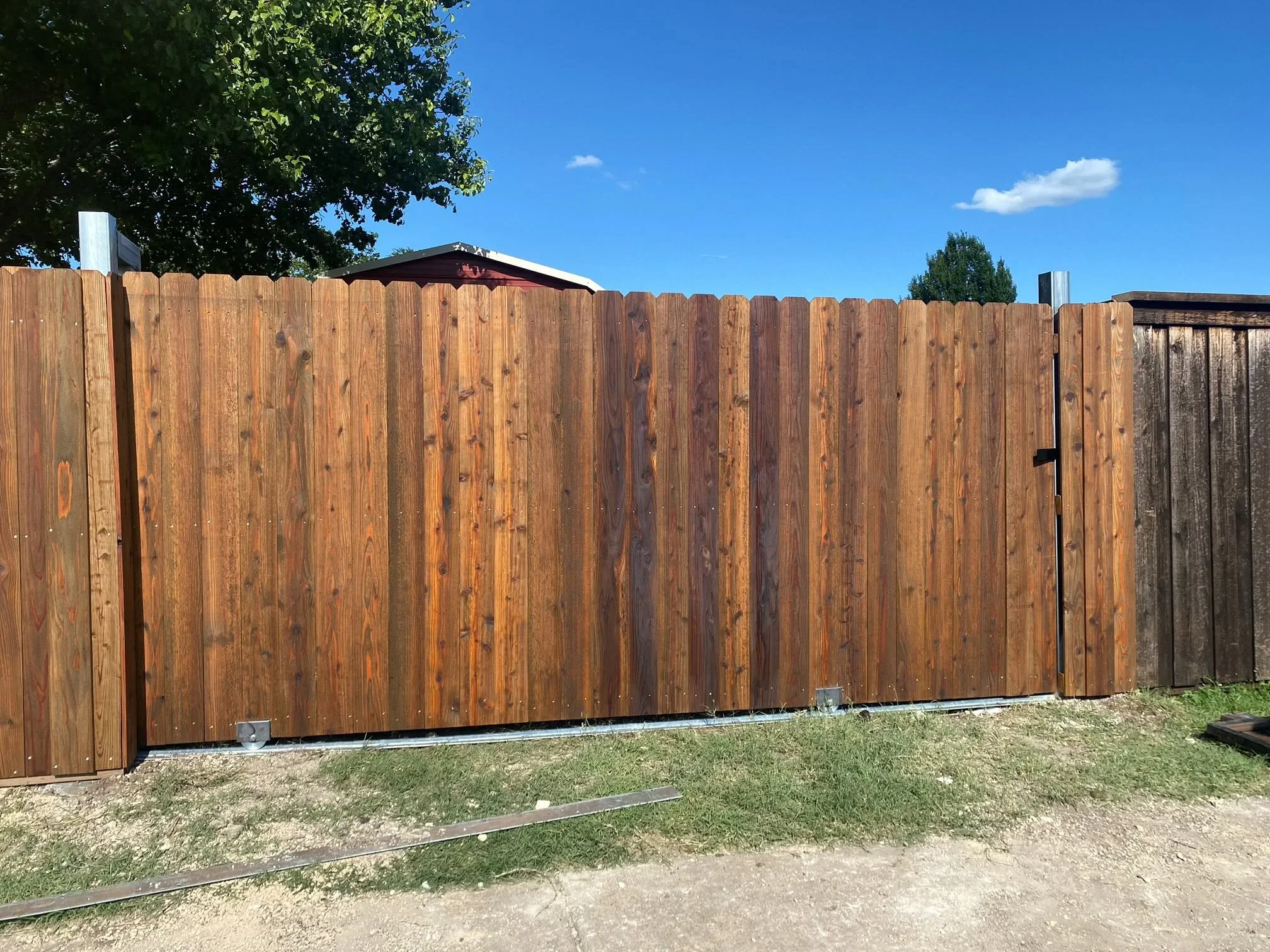 Newly installed wood privacy fence with vertical cedar boards and metal posts