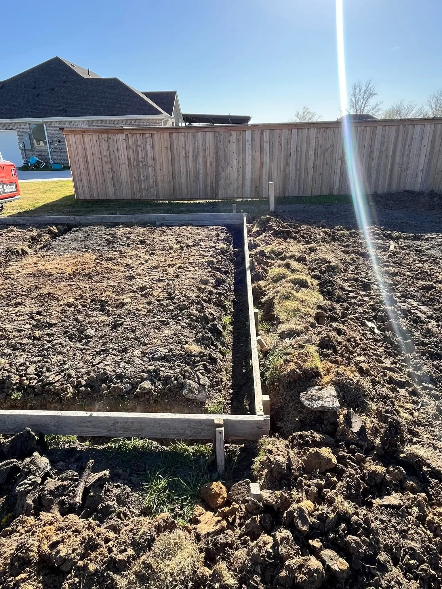 Wooden privacy fence with concrete footings and metal reinforcement posts during installation