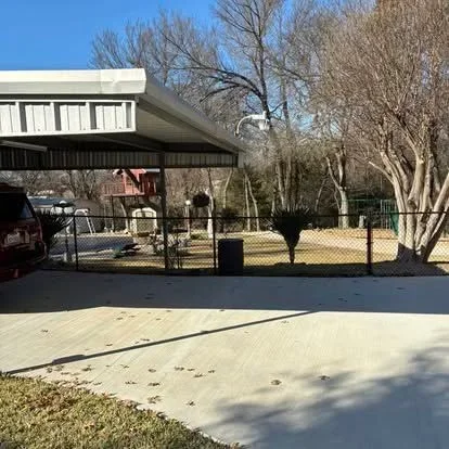 Chain-link fence with galvanized steel posts installed around residential property with concrete driveway