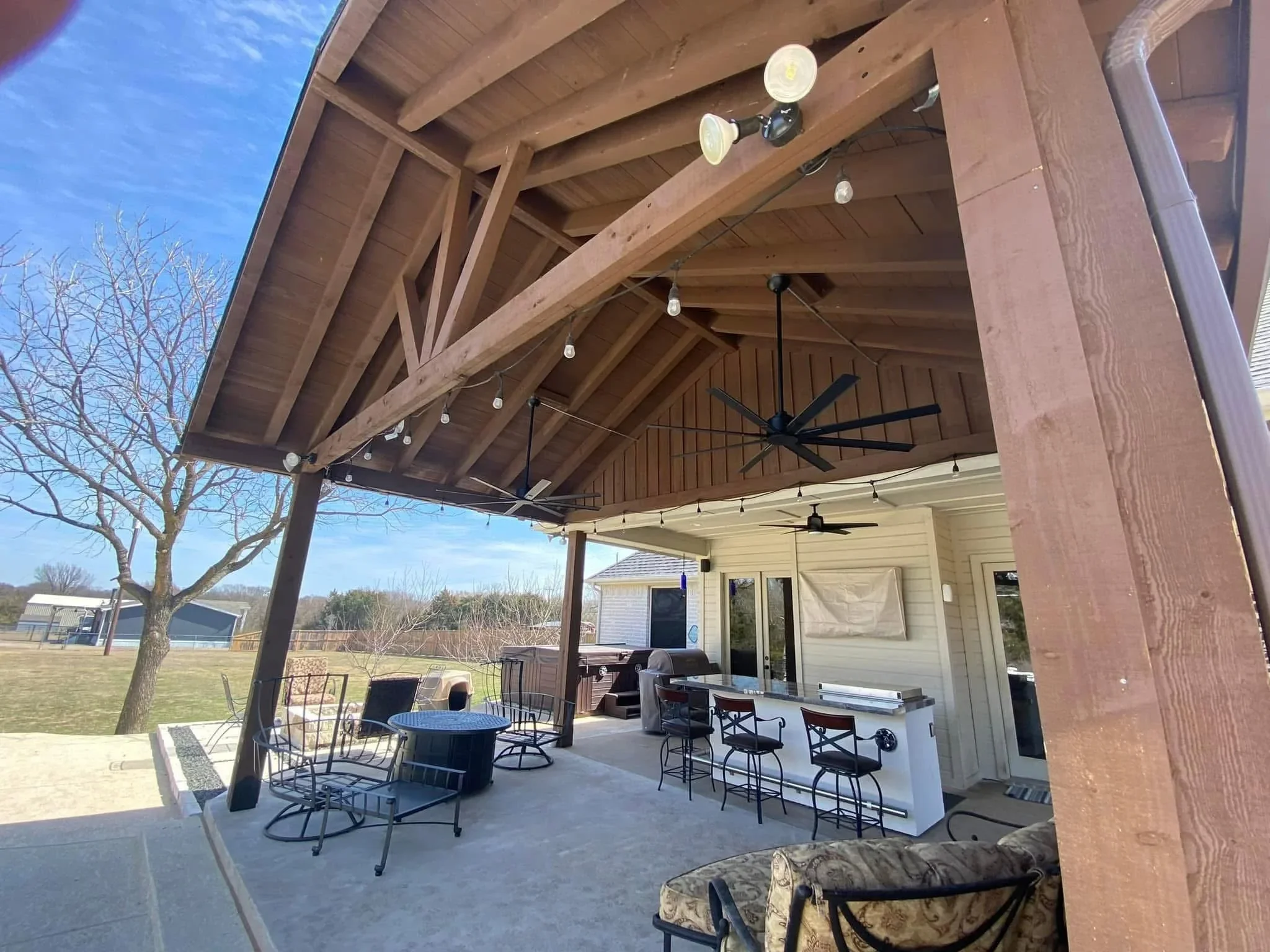 Covered patio with timber beams, ceiling fans, concrete pad, fire pit, and outdoor kitchen counter